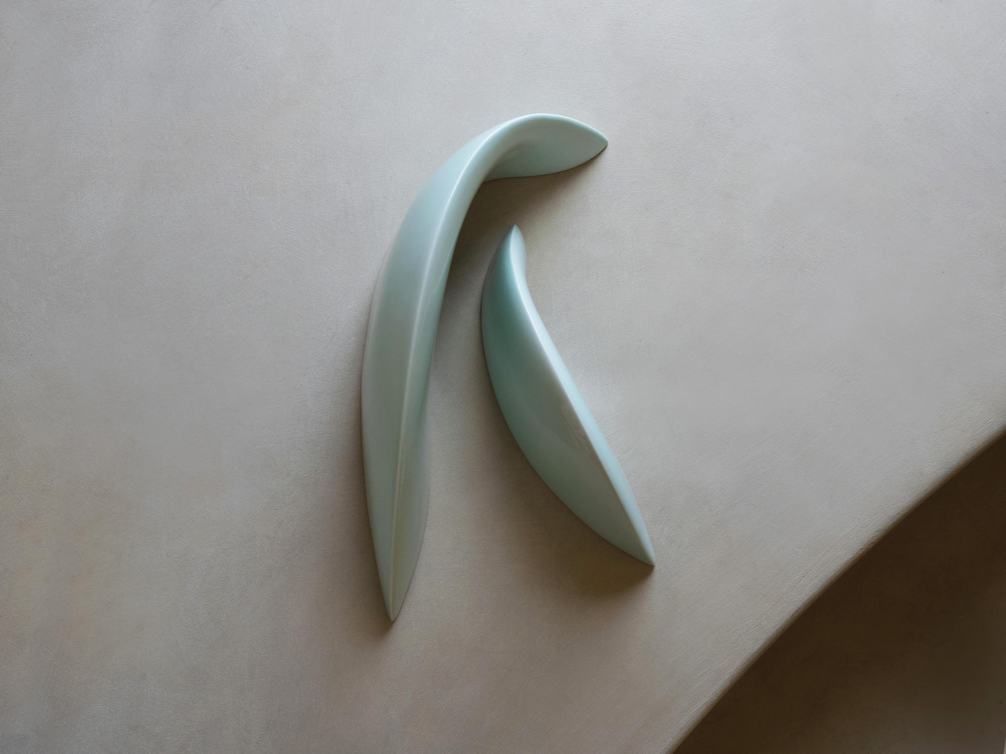 This is a ceramic celadon sculpture pair by Soo Joo, designed to be an abstract table sculpture. Reminiscent of two Isles, someone crossing their legs, 송편 (Korean dumplings), succulent leaves, a hug, or a mama and baby whale, these Korean celadon