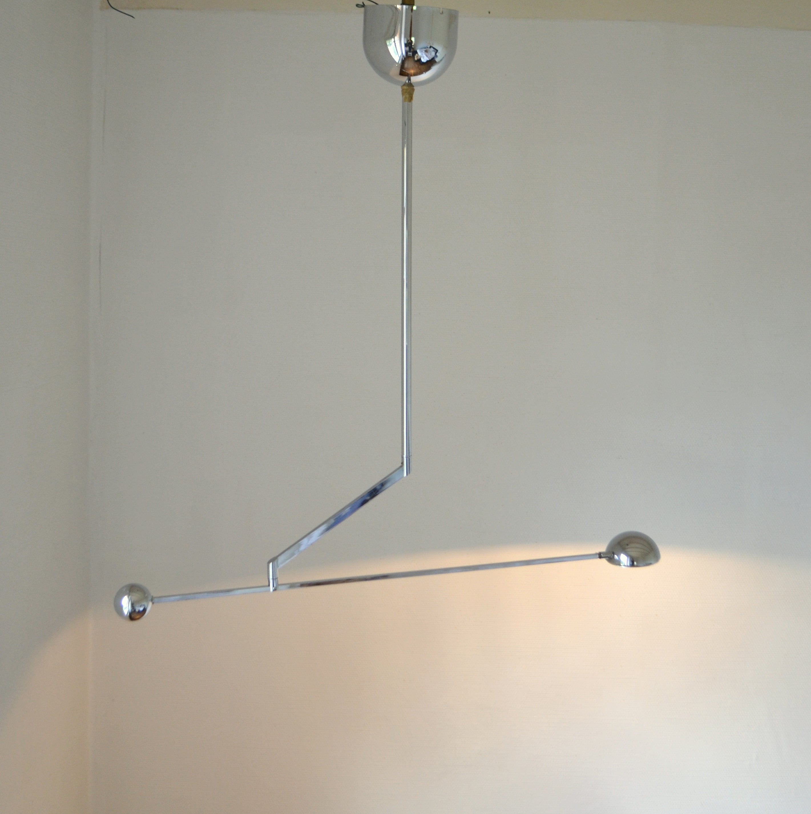 Minimalist counterbalance chrome pendant lamp with spotlight is super flexible, with an arm adjustable to 180 degrees. The halogen light source is attached to a long arm holding a spherical counter weight. The arm sits on an angled stand with