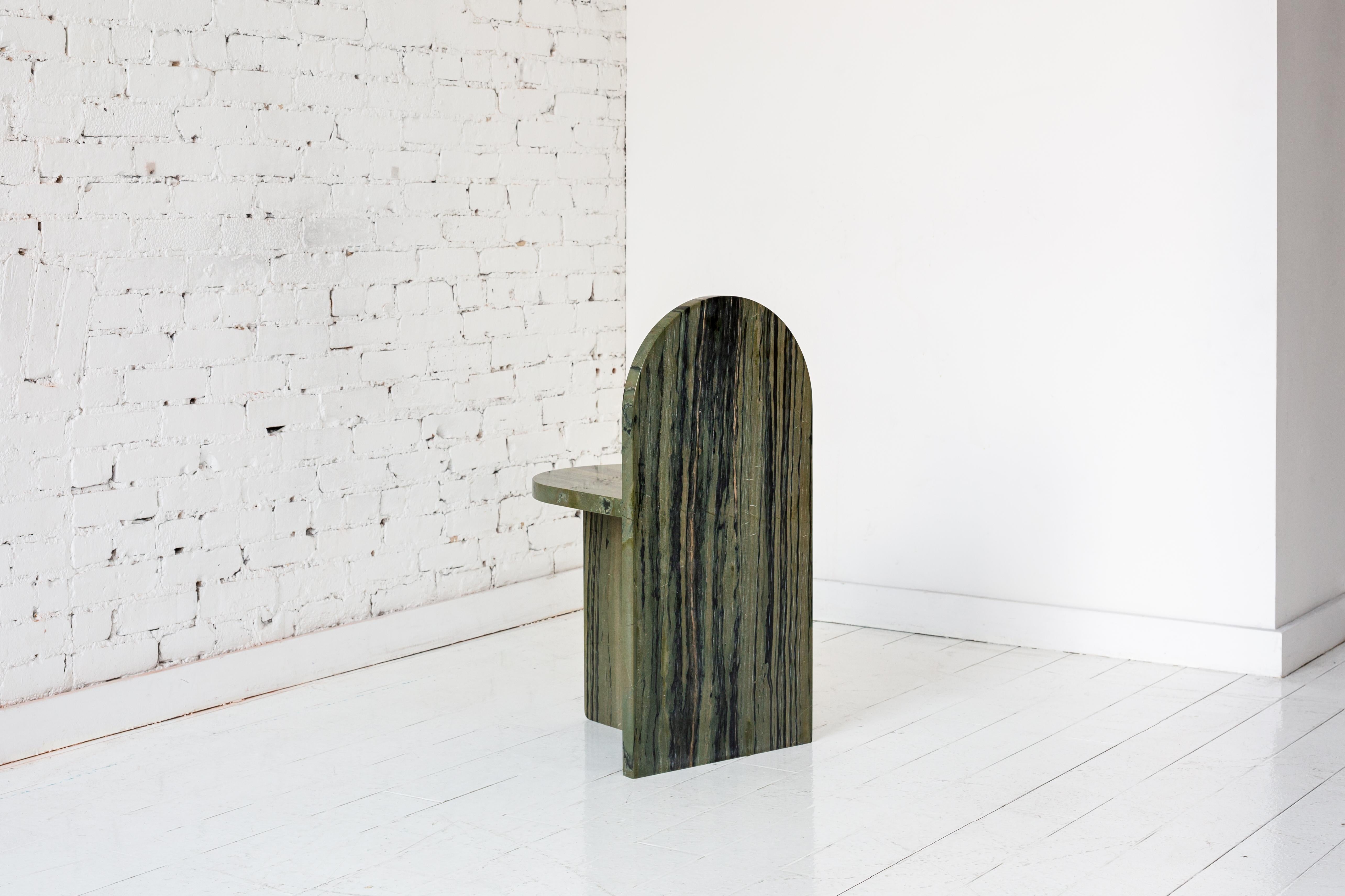 This minimal, occasional side chair is made of three intersecting planes with the backrest resembling a traditional tombstone shape. 

Shown in Verde bamboo, a Brazilian quartzite, and blue Bahia, a Brazilian granite. Available in a variety of