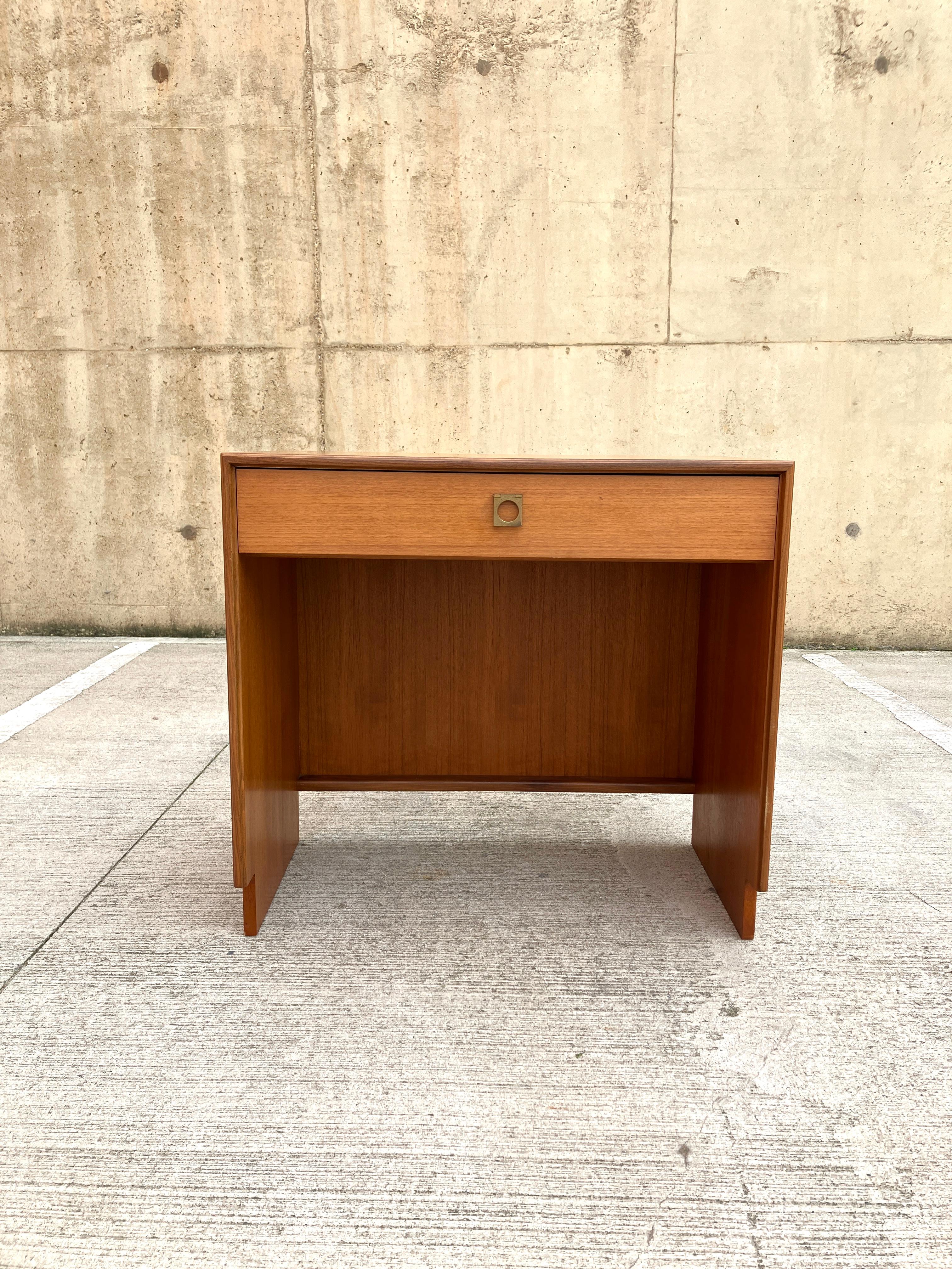 A compact mid-century desk/dressing table with a drawer by G Plan. 

Dating from 1967 and designed by Richard Bennett, this teak dressing table has a minimalist and modern design. The desk displays a clear Danish influence that many British
