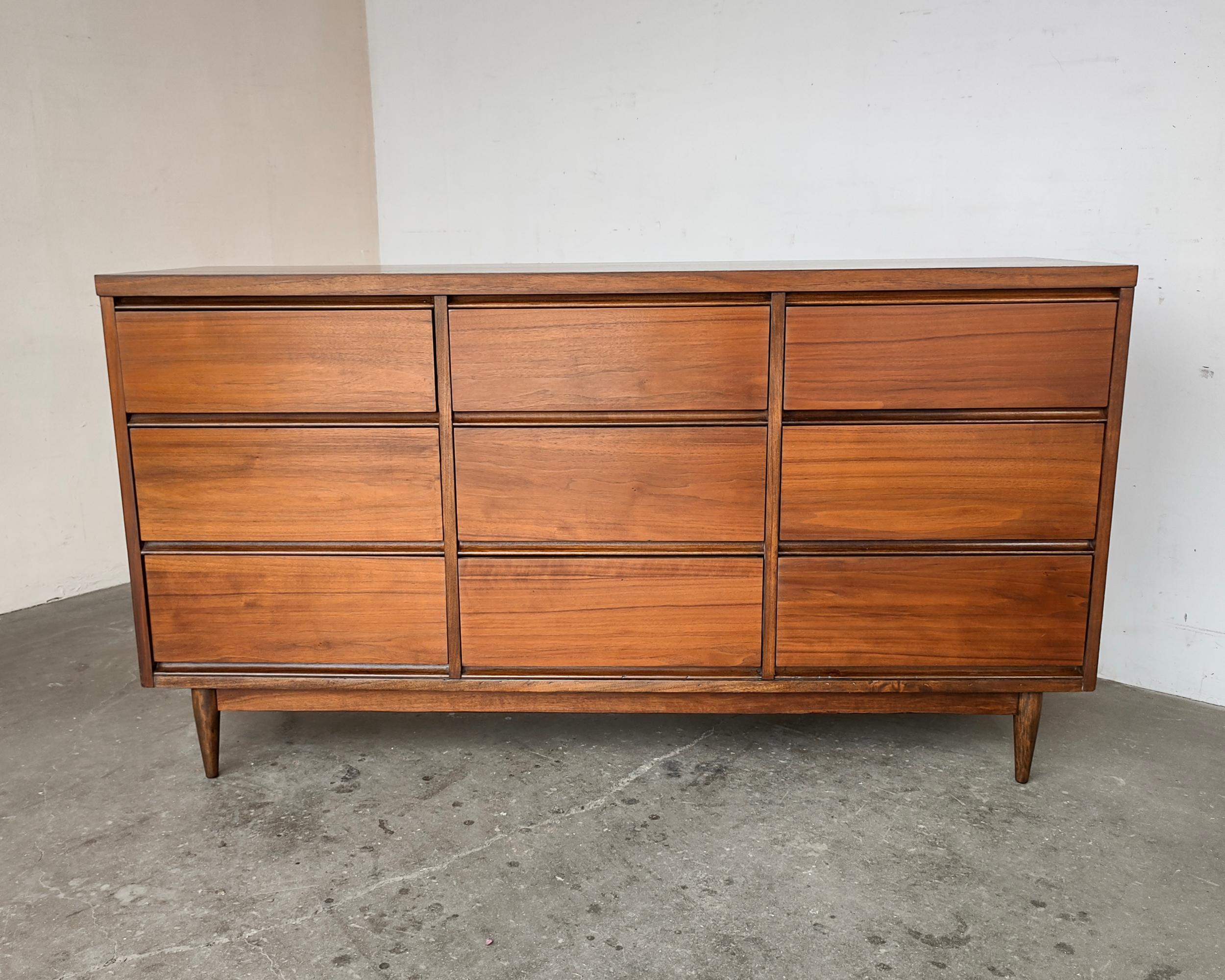 Professionally restored Mid-Century Modern nine-drawer walnut dresser circa 1960s. Classic minimal design featuring beautiful walnut wood grain covering entire body and tapered legs. Overall great condition - some light wear consistent with vintage