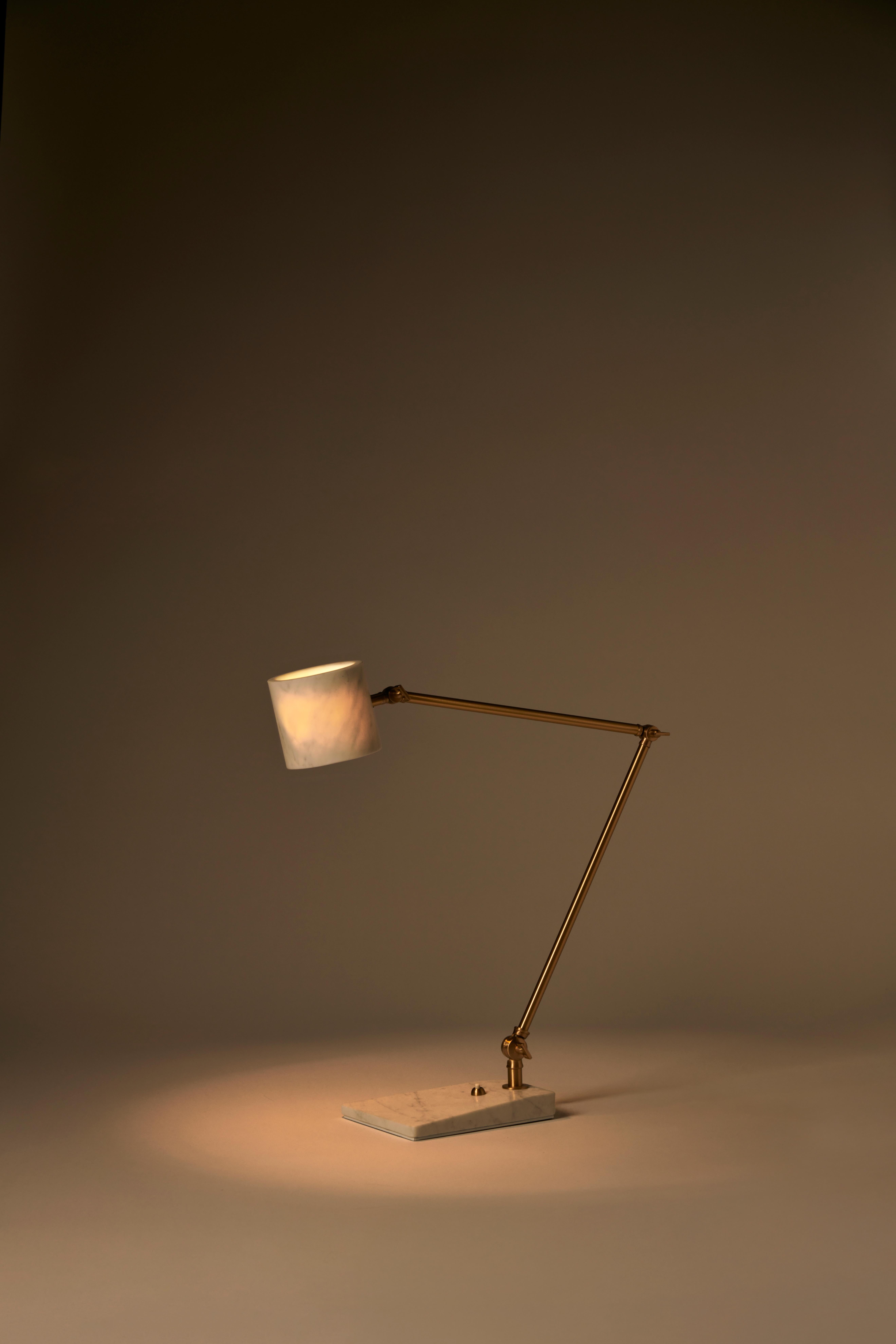 The Flamingo desk lamp is characterized by the contrast between the volumes of its elements: the thinness of the adjustable angle brass stem contrasts with the unusual adjustable marble shade. The lamp’s clean, linear silhouette cap- tures a modern