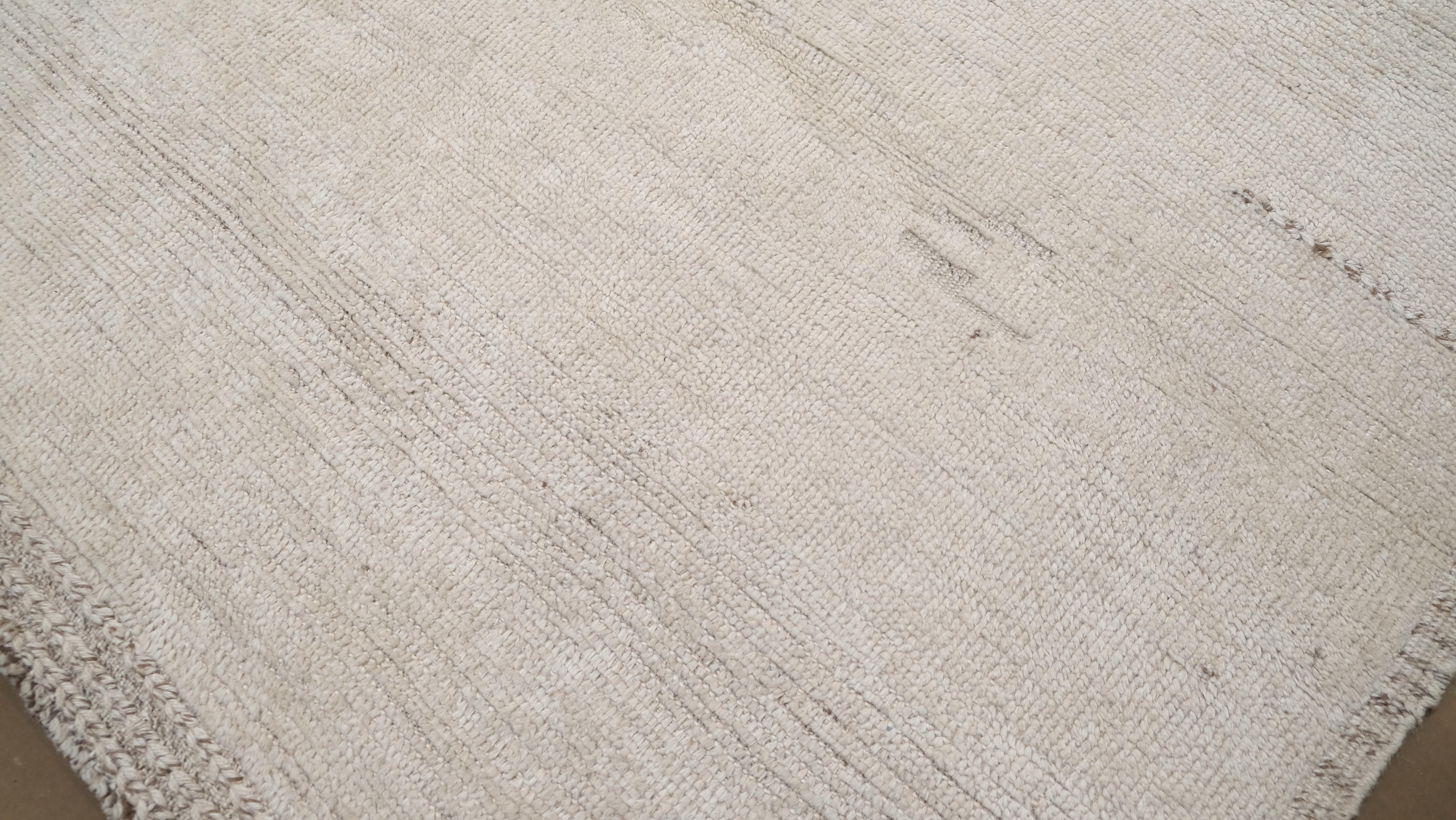 Dieser minimalistische, handgeknüpfte Wollteppich aus Pakistan wertet Ihren Wohnraum durch seine schlichte Raffinesse auf. Dieser Teppich mit seiner klaren und ruhigen Ästhetik ist in einer neutralen Farbpalette gehalten. Er eignet sich perfekt für