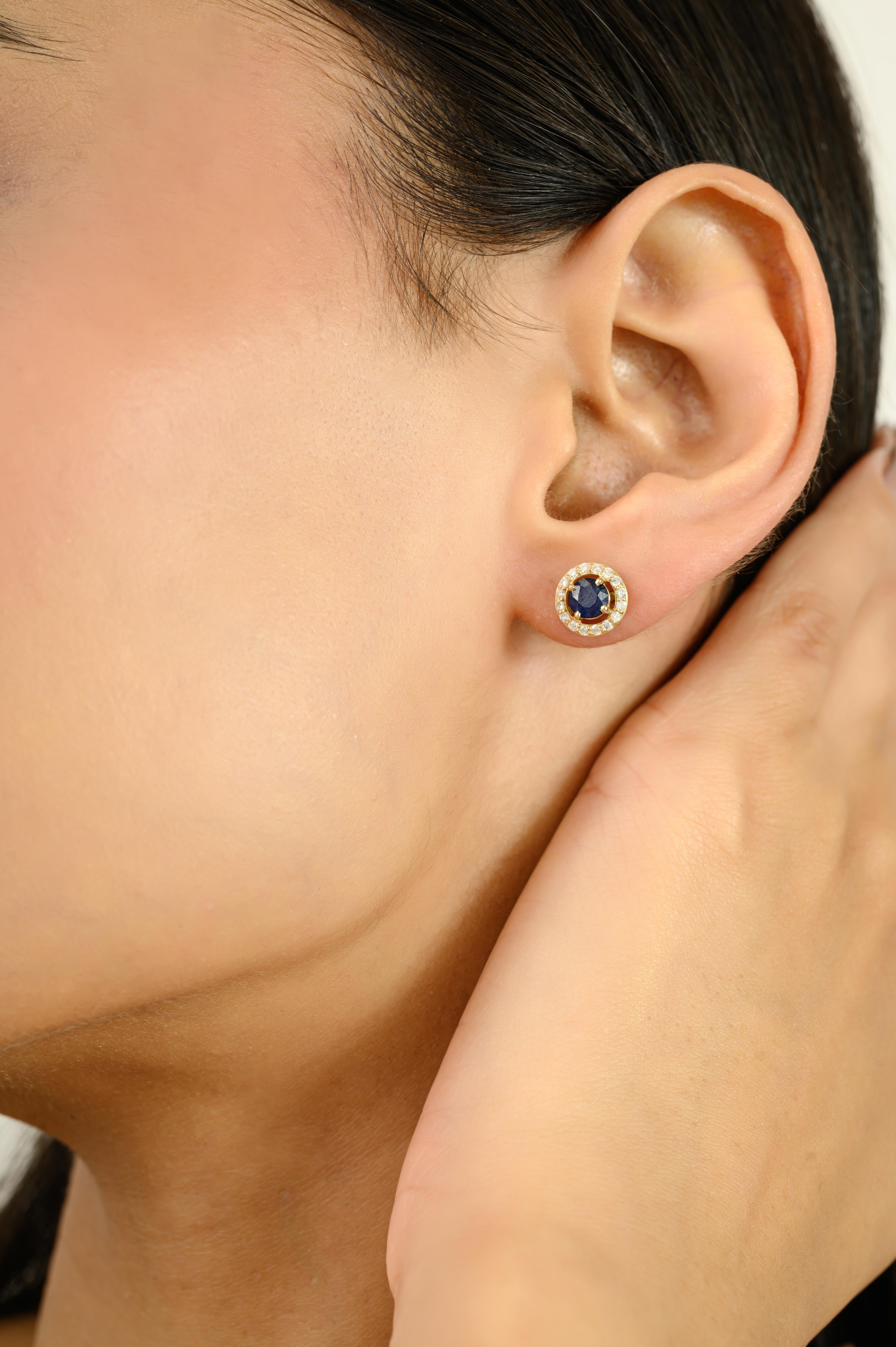 Réalisées en luxueux or jaune 14 carats, ces superbes boucles d'oreilles sont ornées de saphirs bleus d'un poids total de 1,13 carat, élégamment sertis dans une monture classique à quatre griffes. Les pierres centrales sont entourées d'un halo de