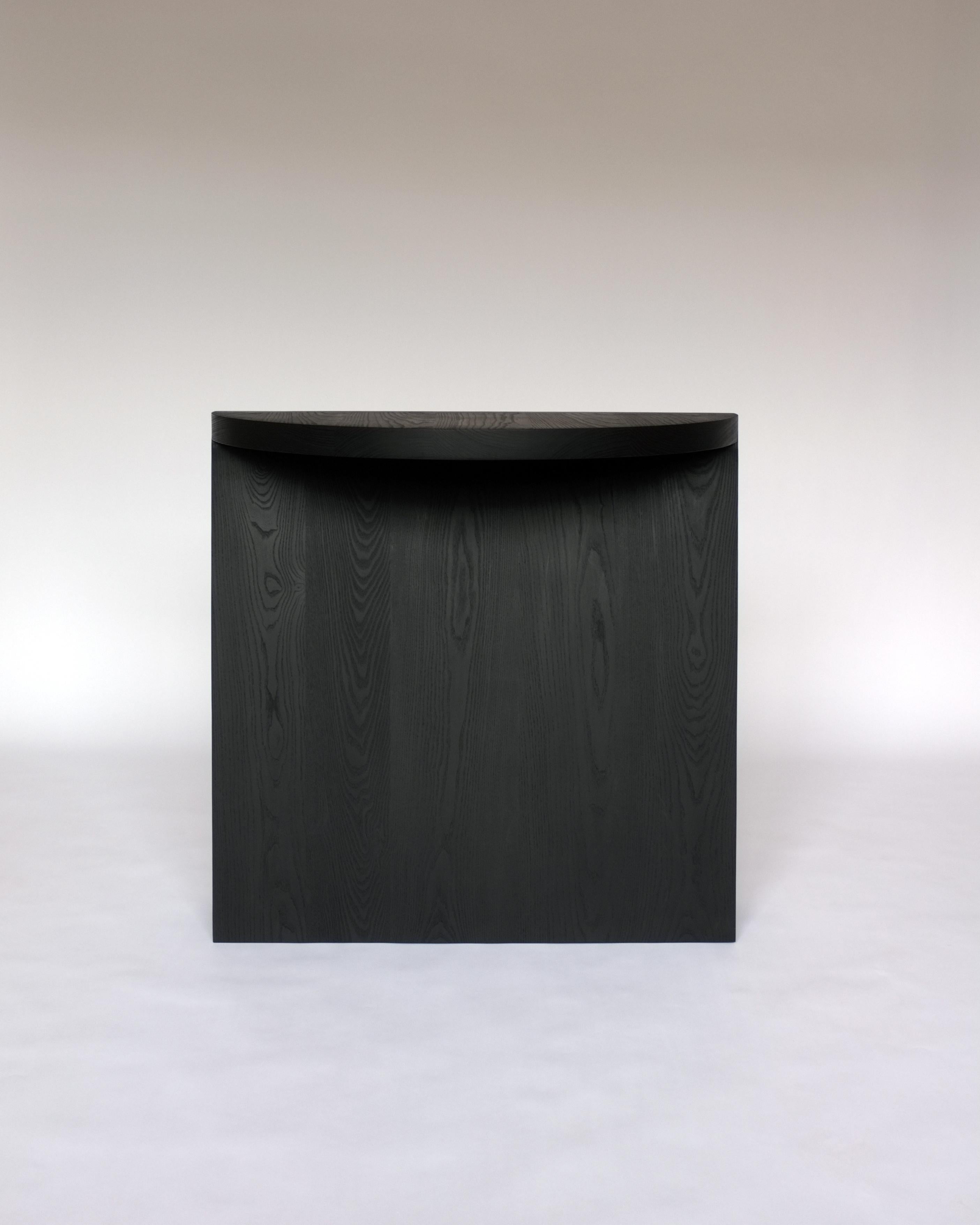Wedge console table by Campagna in black dyed ash.

This sculptural, contemporary wooden console table features a simple half round top and a large pedestal base. The interaction of the two simple geometric forms creates moments of shifting