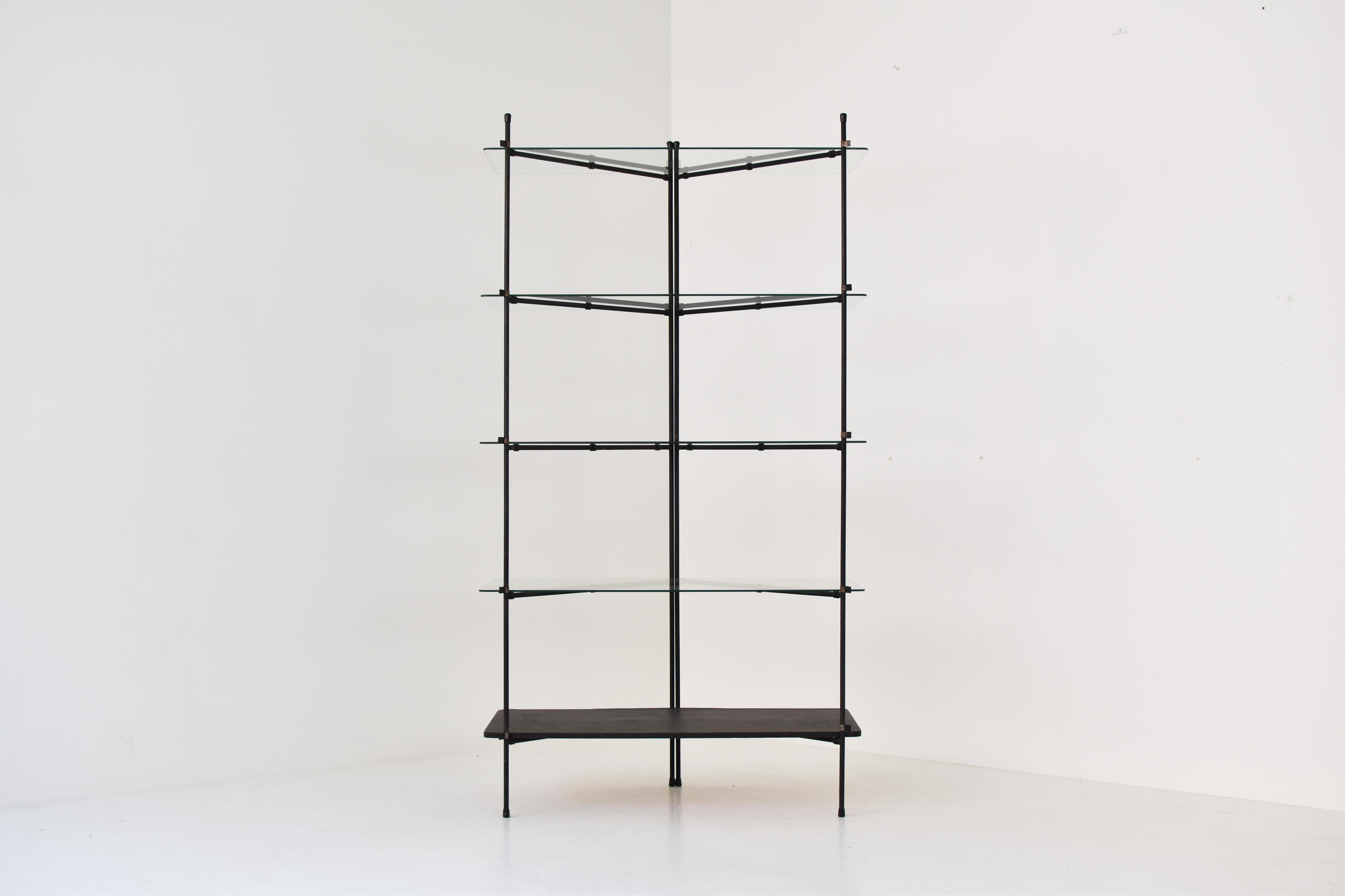 Minimal shelving / display unit dating from the 1960s. This freestanding cabinet has four glass shelves and one in black lacquered wood. The frame is made out of black lacquered steel. The glass shelves show some age related marks from age and use.