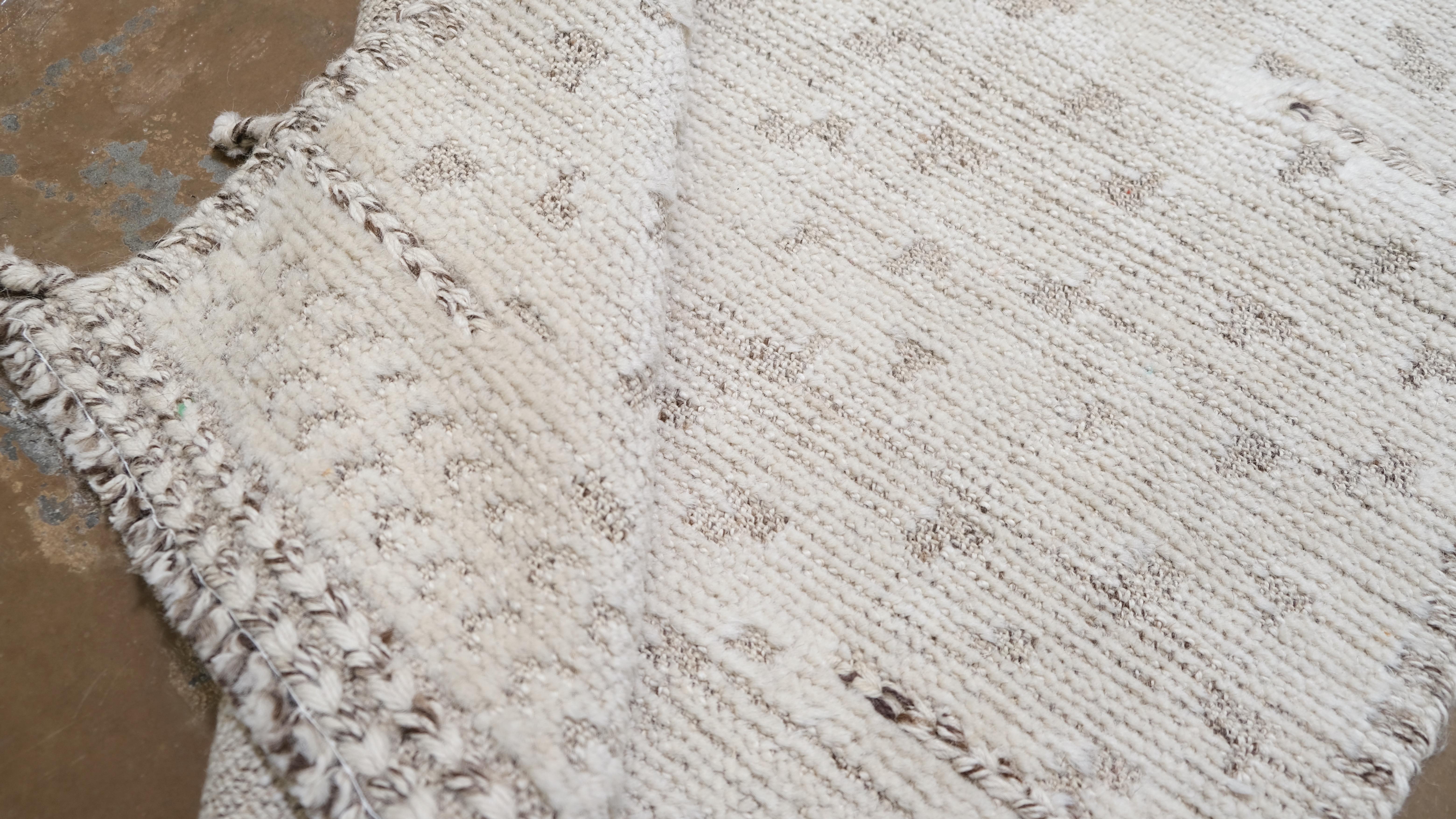 Bringen Sie mit diesem handgeknüpften Wollteppich schlichte Eleganz in Ihr Zuhause. Mit seinem minimalistischen Design in einem sanften Elfenbeinton mit subtilen abstrakten Mustern ist dieser Teppich der Inbegriff moderner Raffinesse. Die zarte