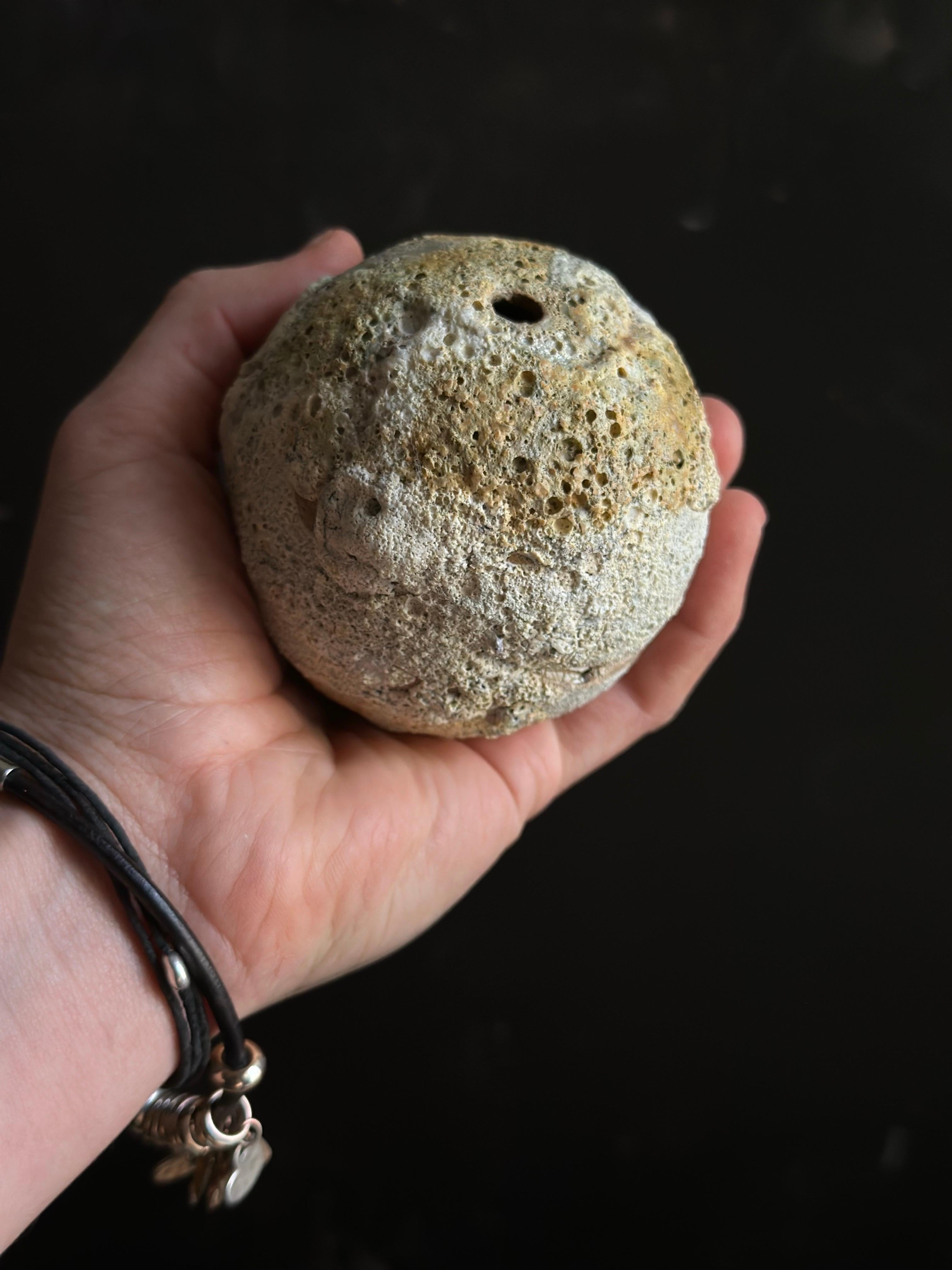 This hand-thrown ceramic bud vase resembles a weathered stone, with its porous texture and subtle earthy hues. The naturalistic design brings a grounding element to modern rustic or wabi-sabi interiors. Perfect for styling as a sculptural accent or