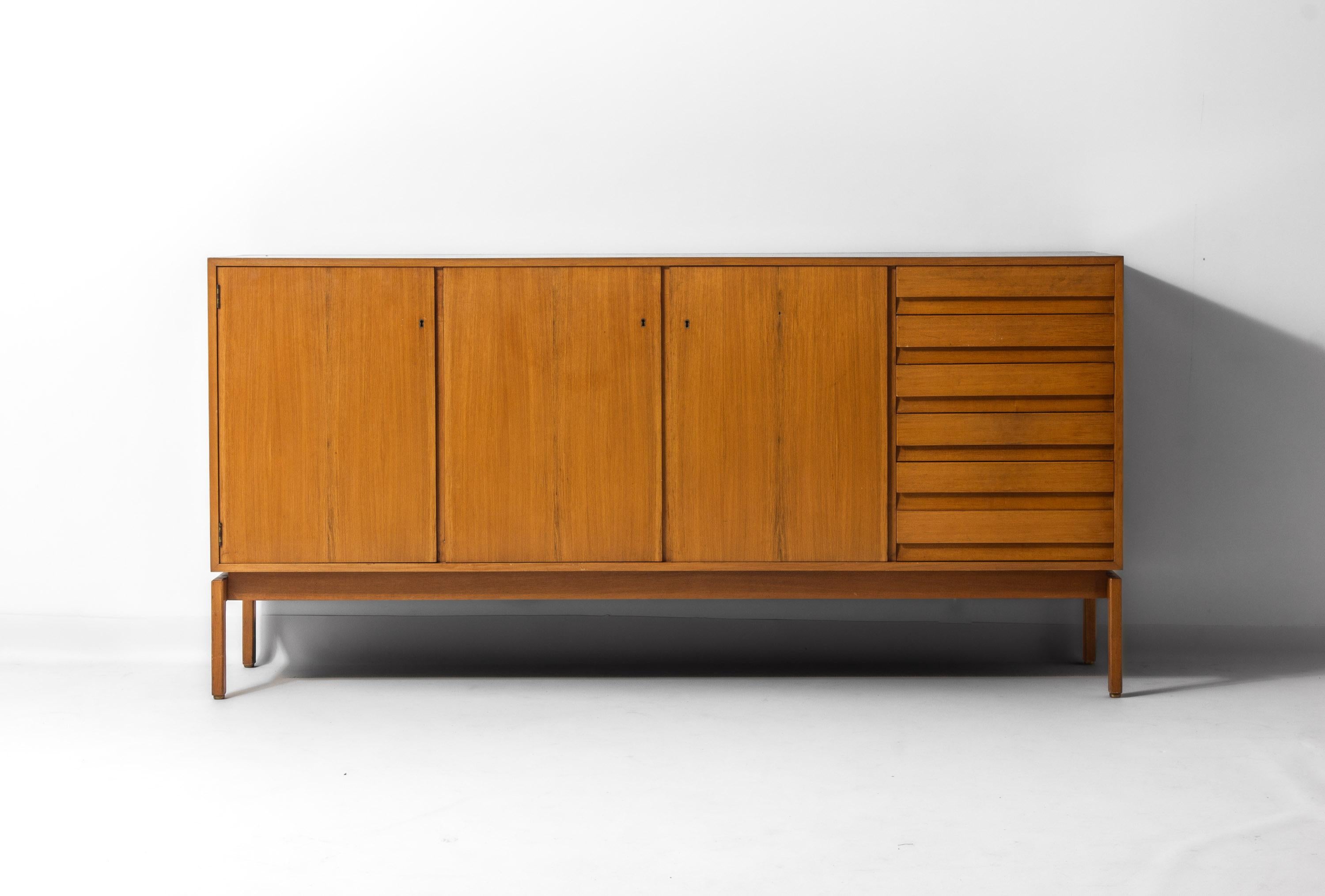 Sideboard from the Abstracta series, designed by Jos De Mey and produced by Van den Berghe-Pauvers in Ghent, Belgium, during the 1960s. Made of oak with a warm honey tone, the piece stands on raised legs that give it a light, floating appearance.