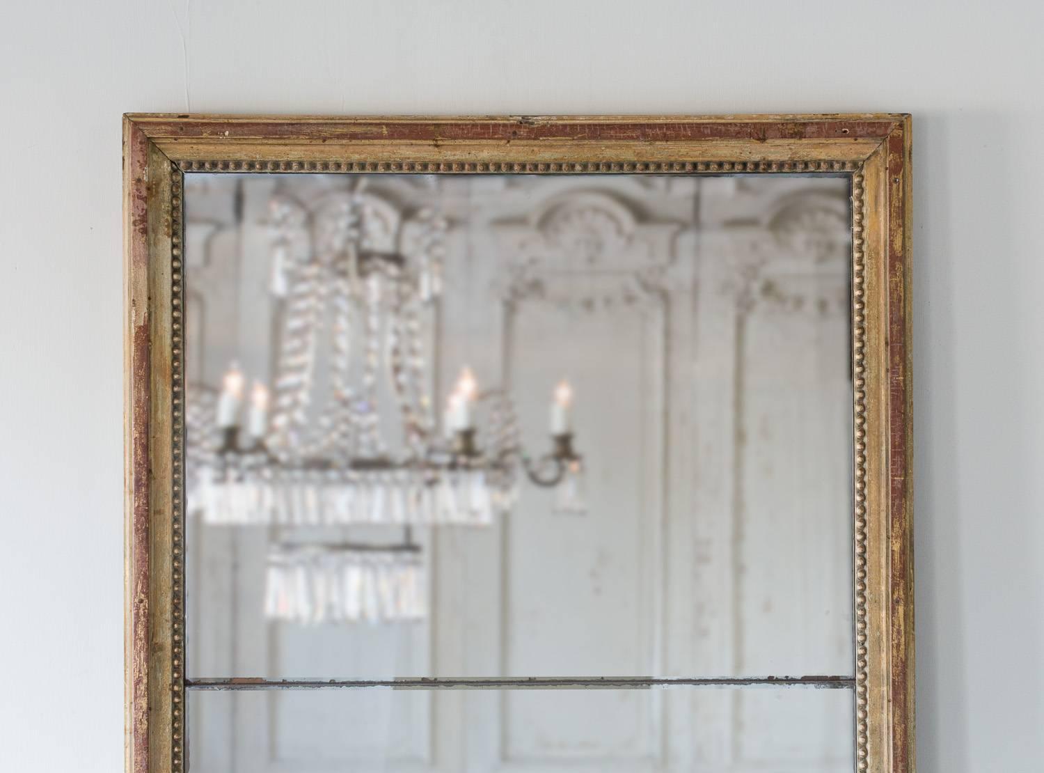 Simple, two-part mirror in classic, Louis XVI style. A string of beads decorate the inner frame keeping this beauty simple and effective. The original, mercury glass is in wonderful condition considering its age. Minor scratches and distressing adds