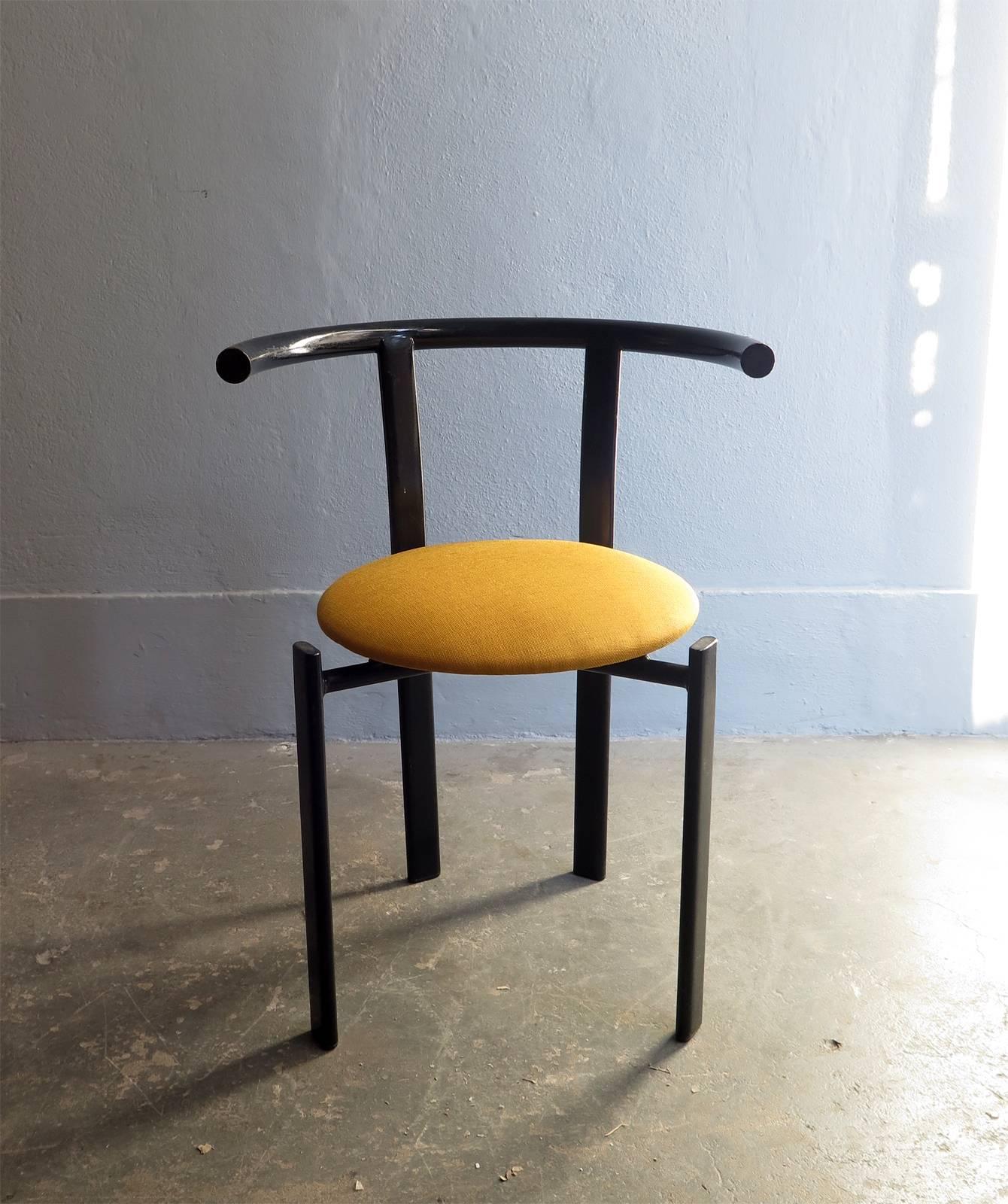 Minimalist black metal chair with yellow fabric seat.