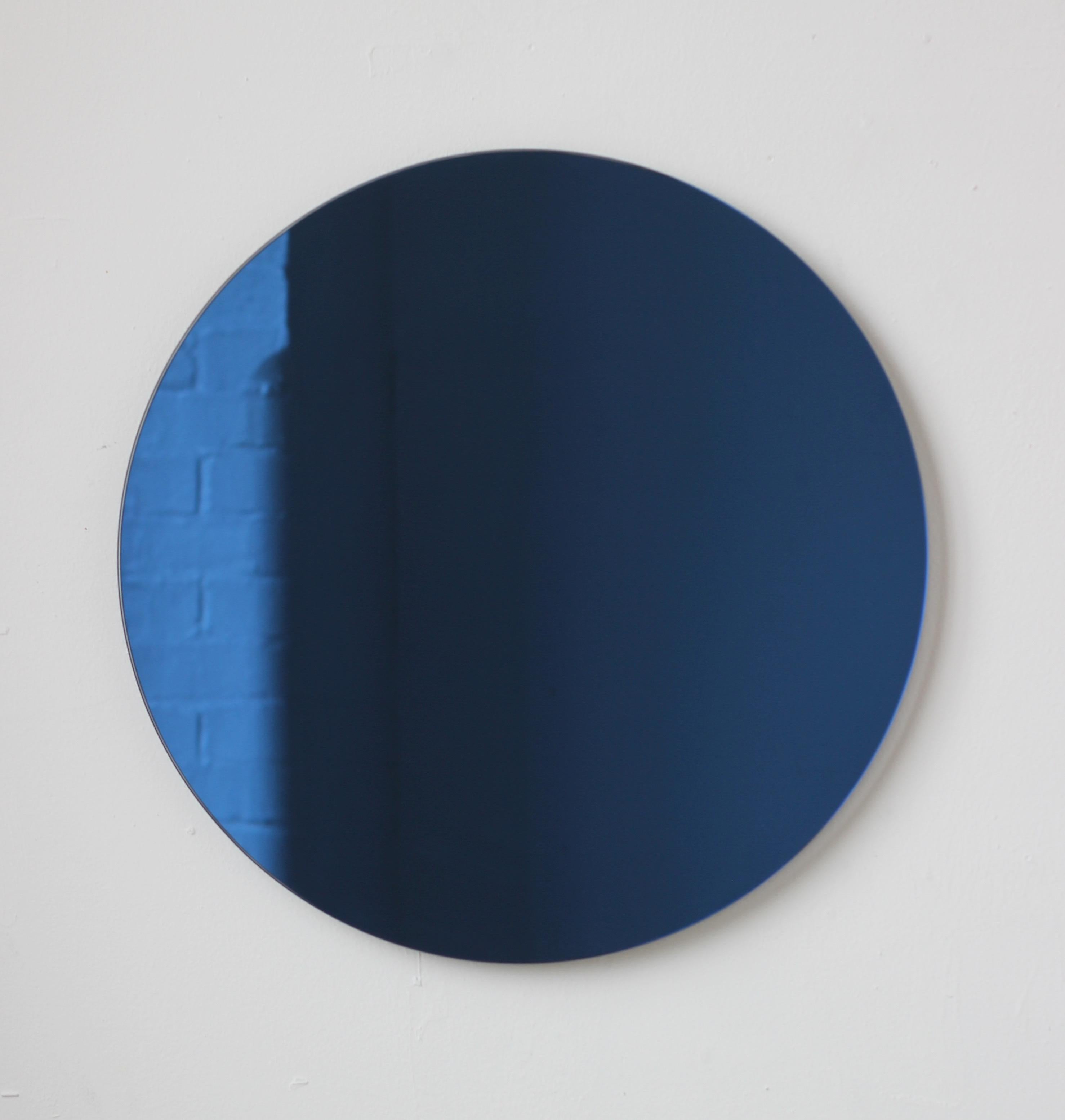 Charmanter und minimalistischer runder, rahmenloser, blau getönter Orbis™-Spiegel mit Schwebeeffekt. Hochwertiges Design, das dafür sorgt, dass der Spiegel perfekt parallel zur Wand steht. Entworfen und hergestellt in London, UK.

Ausgestattet mit