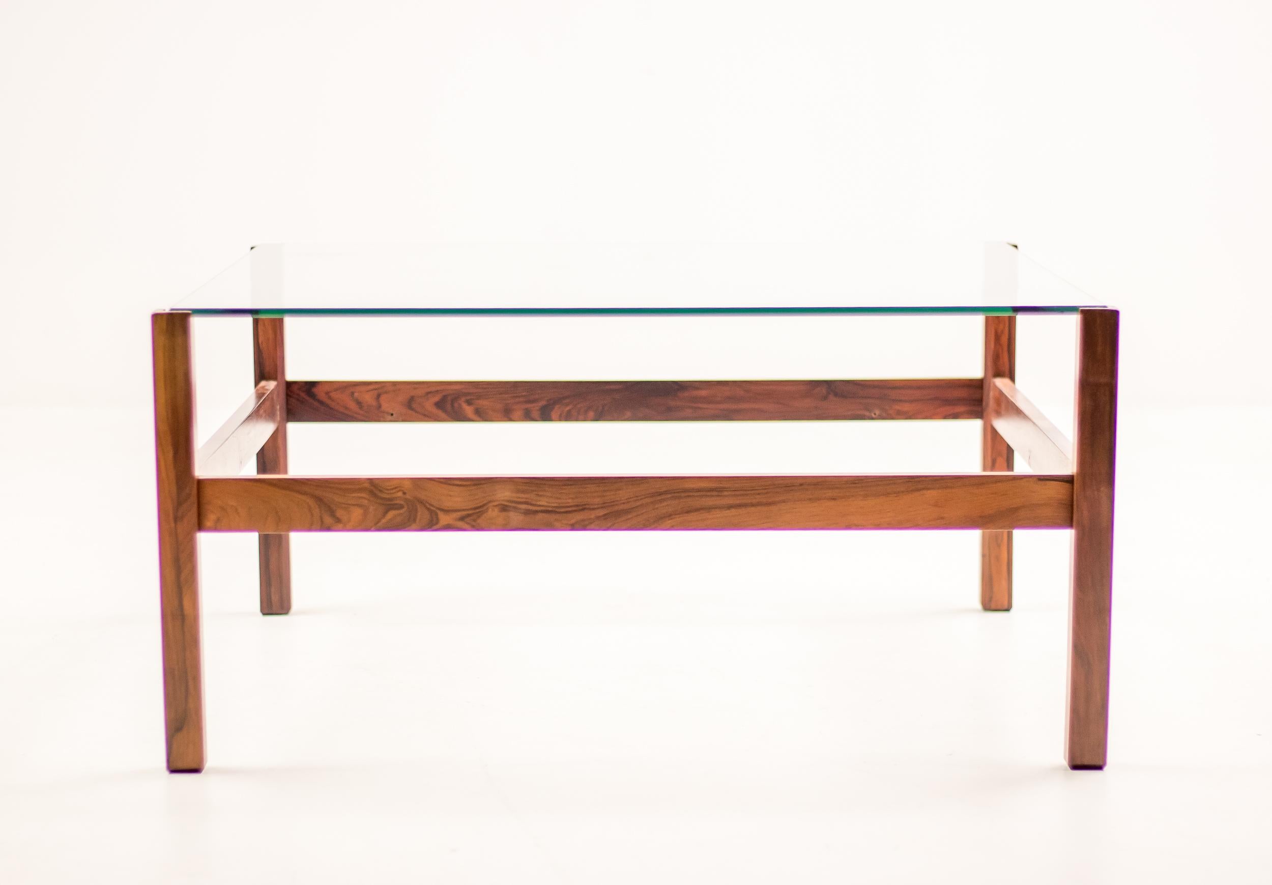 Beautiful Brazilian rosewood Mid-Century Modern architectural coffee table.
Refined geometrical base in solid rosewood with clear glass top.

Brazilian rosewood, also known as Dalbergia nigra, is a rare and valuable hardwood species that is native