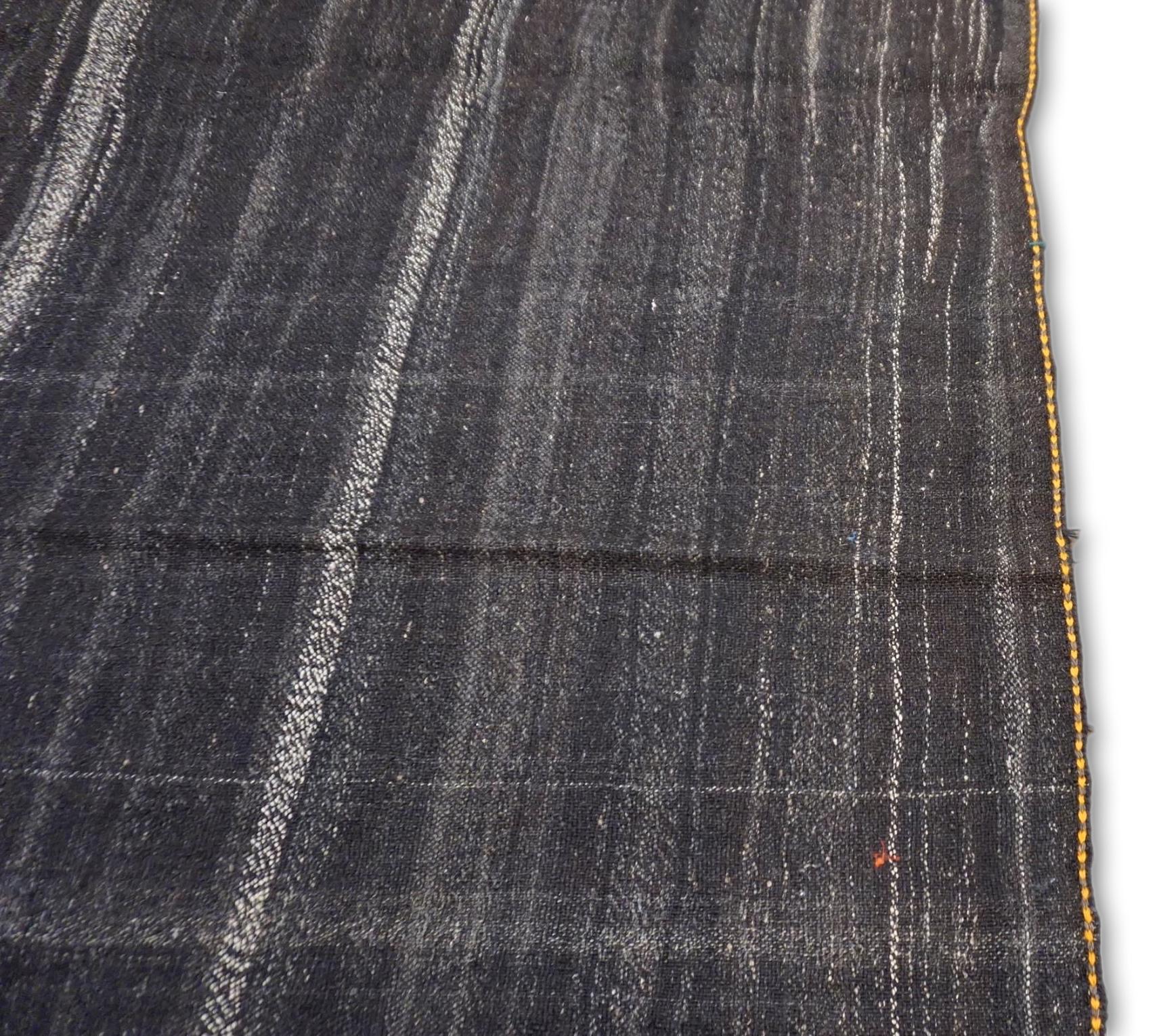This vintage kilim features a refined, minimalist design with subtle striations in gray, brown, charcoal, gold, and tan tones. A delicate row of geometric gold embroidery adds a sophisticated yet understated touch, embodying the traditional