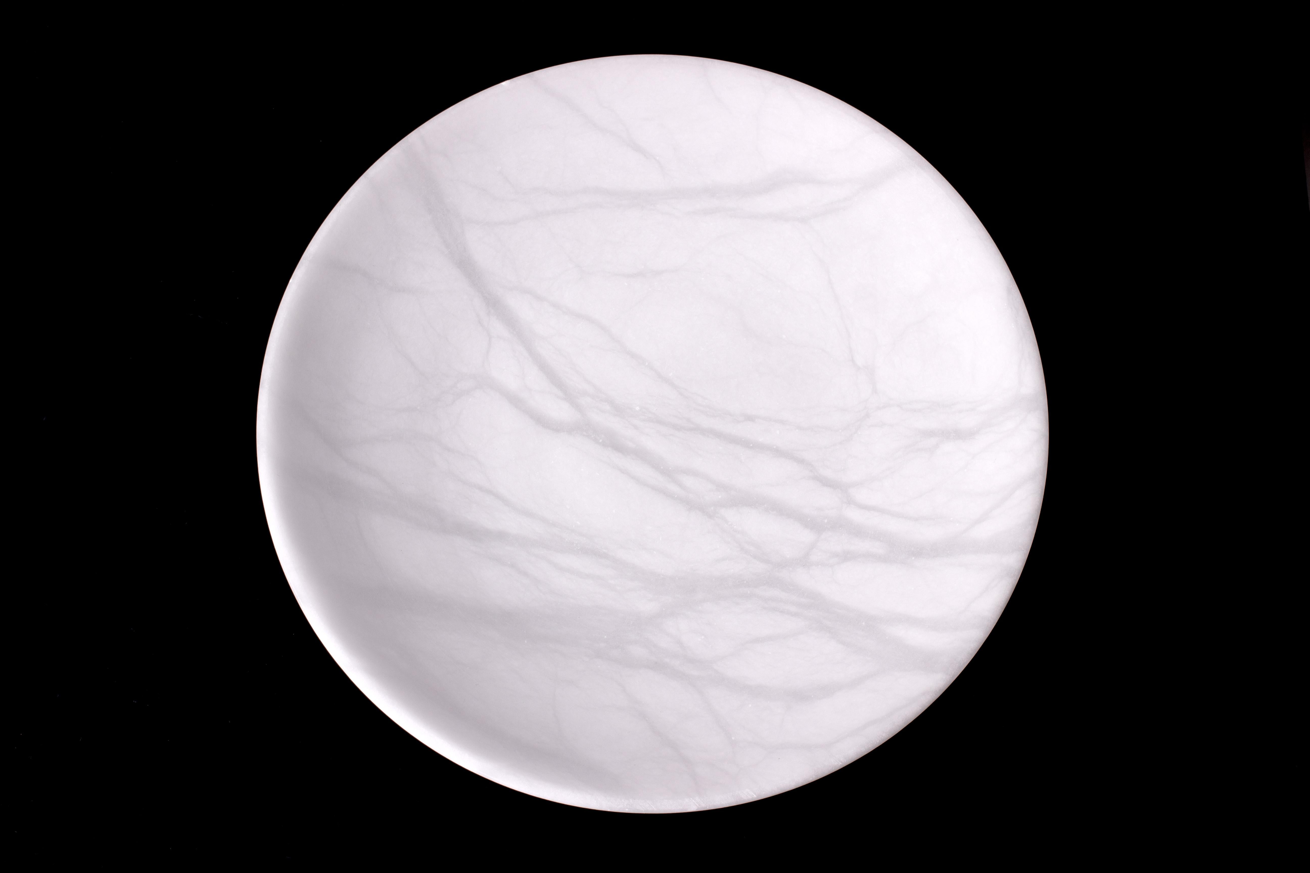 Minimalist sculpted bowl in honed Carrara marble of the fine statuary grade. Pure white stone with white veins of varying transparency. Elegant curved shape with consistent thickness of stone across the dish.