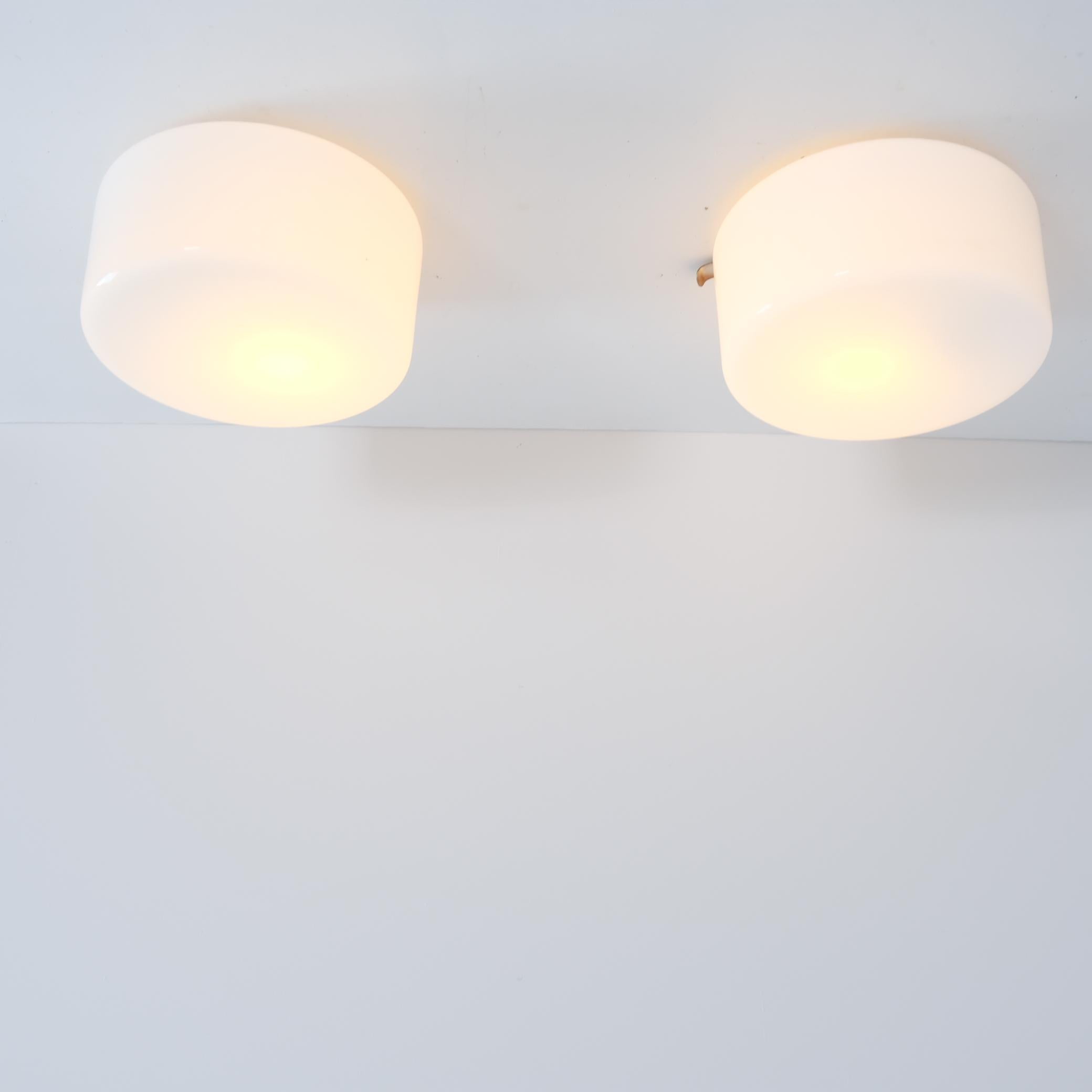 An elegant pair of ceiling lamps in white opaline glass made in Finland in the 1950s. This very minimal design fits easily into any interior. As with a lot of Scandinavian design the beauty of these lamps stems from the simplicity. Nothing extra,