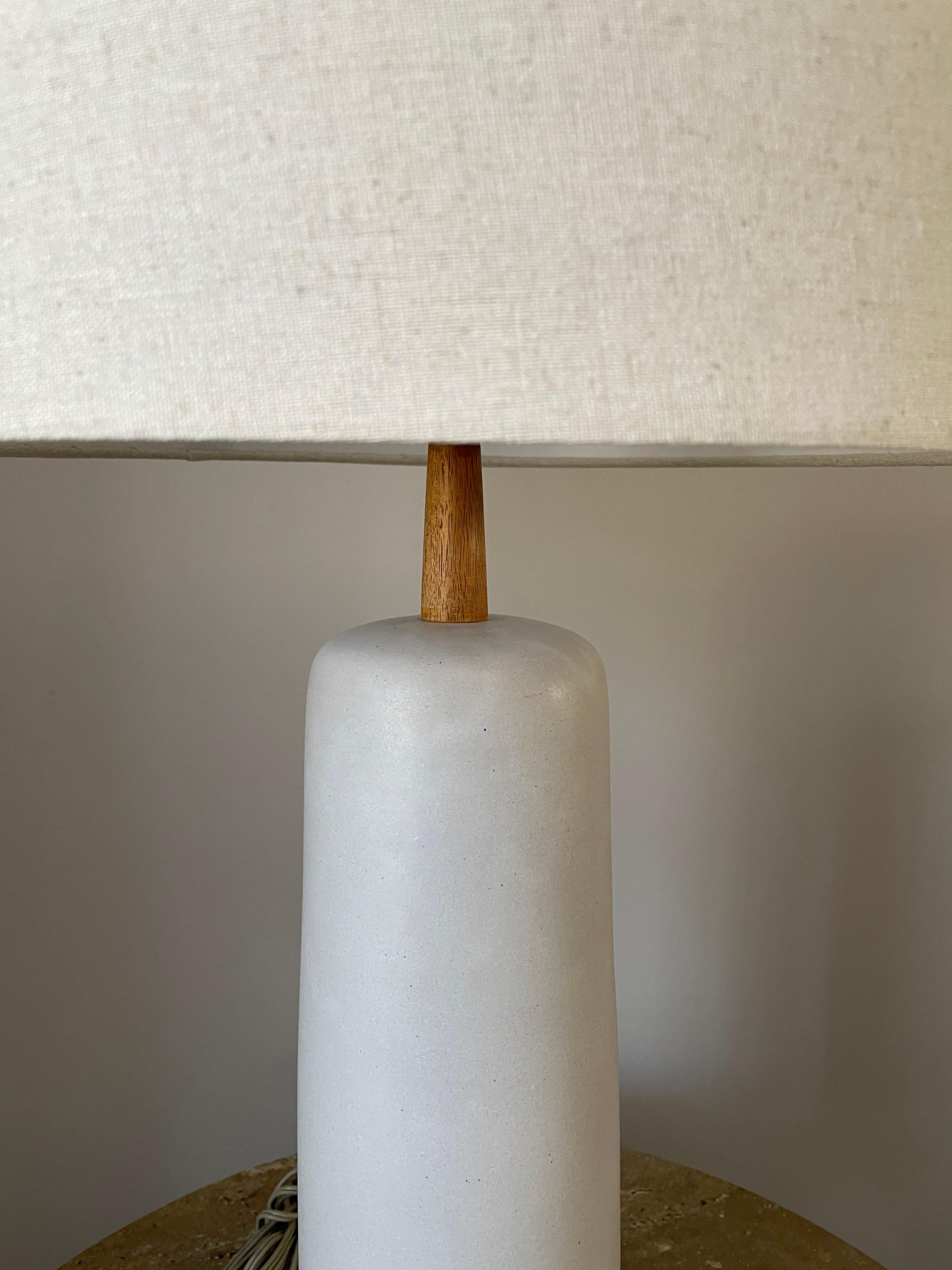 Elegant and timeless table lamp by ceramicist duo Jane and Gordon Martz for Marshall studios. Long off white matte glaze body with walnut neck and elongated walnut finial. 

Measures: Overall
30” tall
15” wide

Ceramic portion 
15.5” tall