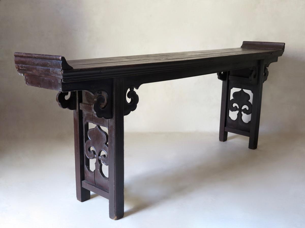 Table d'autel chinoise élégante et chic minimaliste, avec des extrémités de plateau retournées en forme de pagode, et des pieds au design découpé. Le bois a acquis une belle et riche patine.