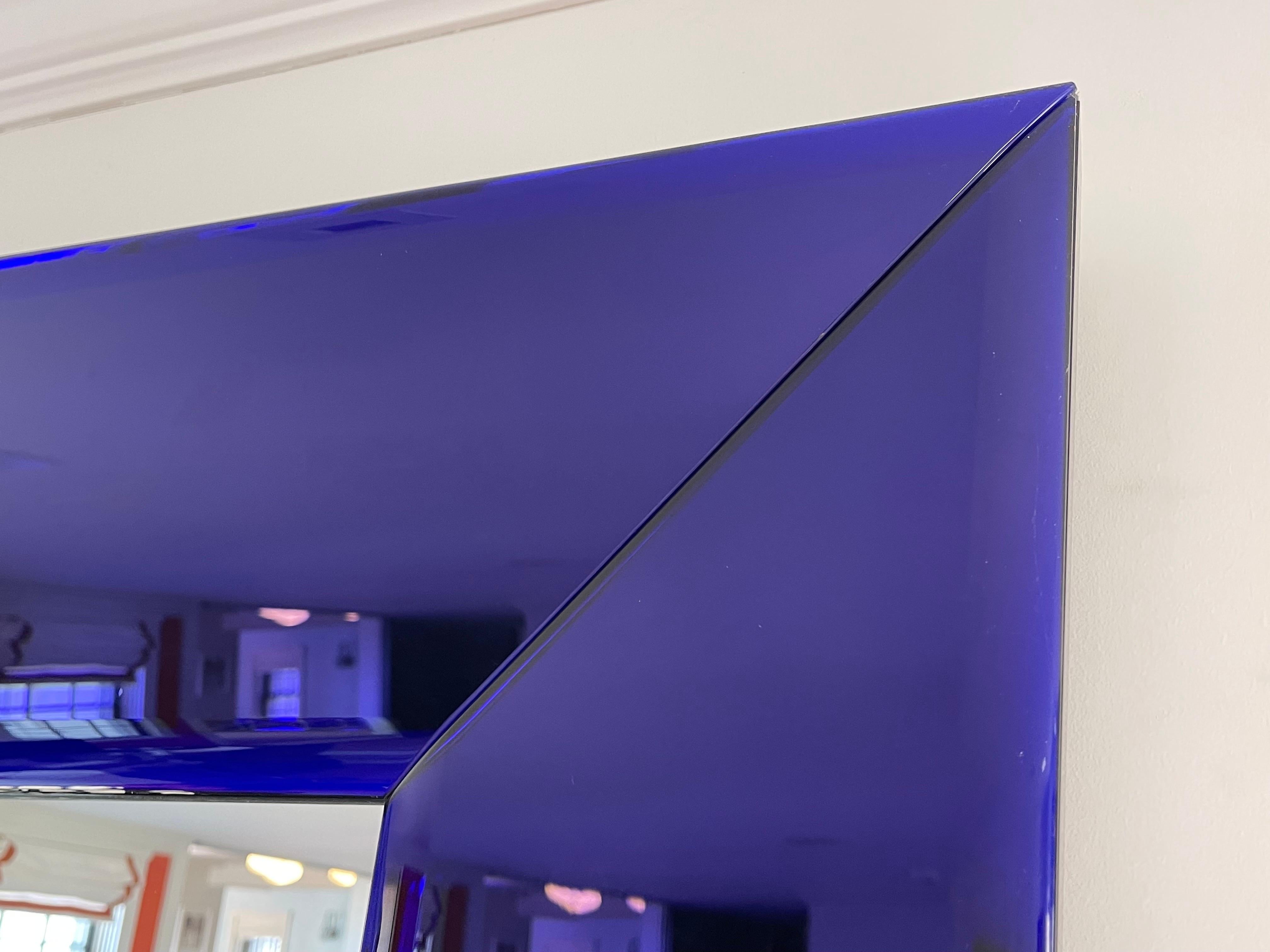 Art Deco style cobalt blue glass framed mirror, beveled throughout. The mirror aspect measures 30 1/2” by 18 1/2”, the frame graduates in width from 29” on the bottom to 36” on the top.