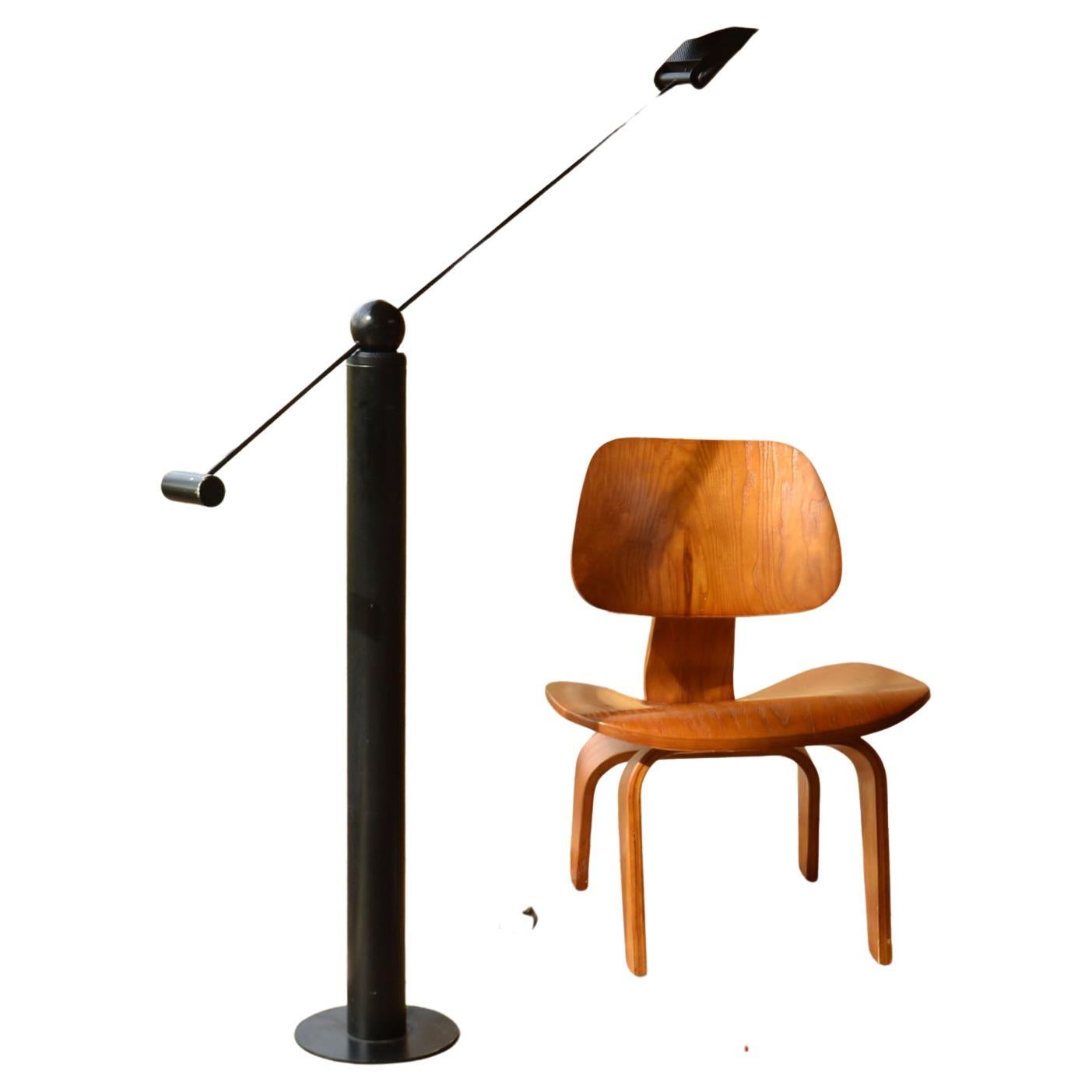 Minimal black metal floor lamp with adjustable arm counterbalancing on cylinder base and halogen light source attributed to Rico & Rosemarie Baltensweiler, Switzerland 1960-70's. The lamp balances on a ball weight resting on a pillar base that