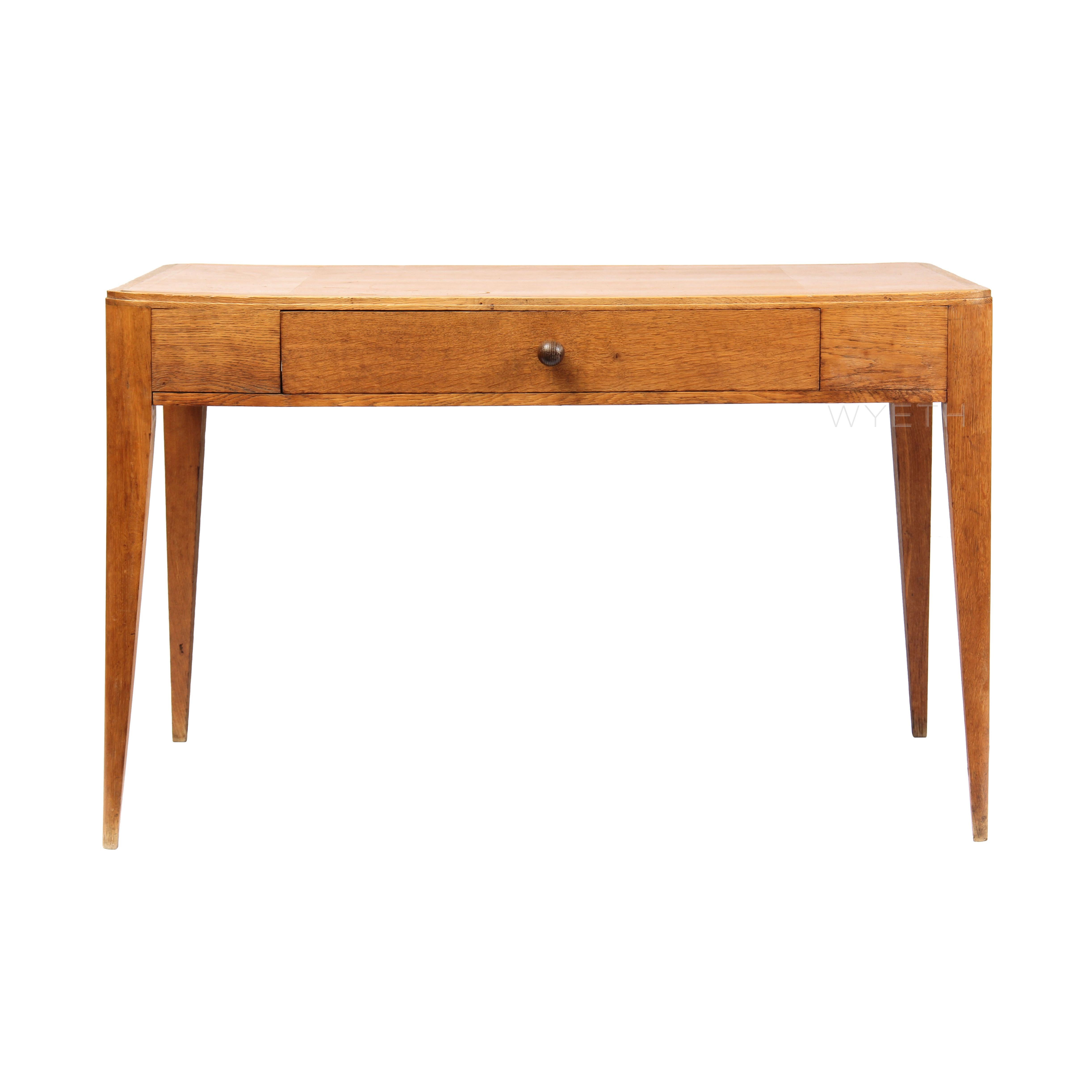 A rectangular oak desk with rounded corners, a tan leather writing surface and a central drawer, on tapered legs.

 