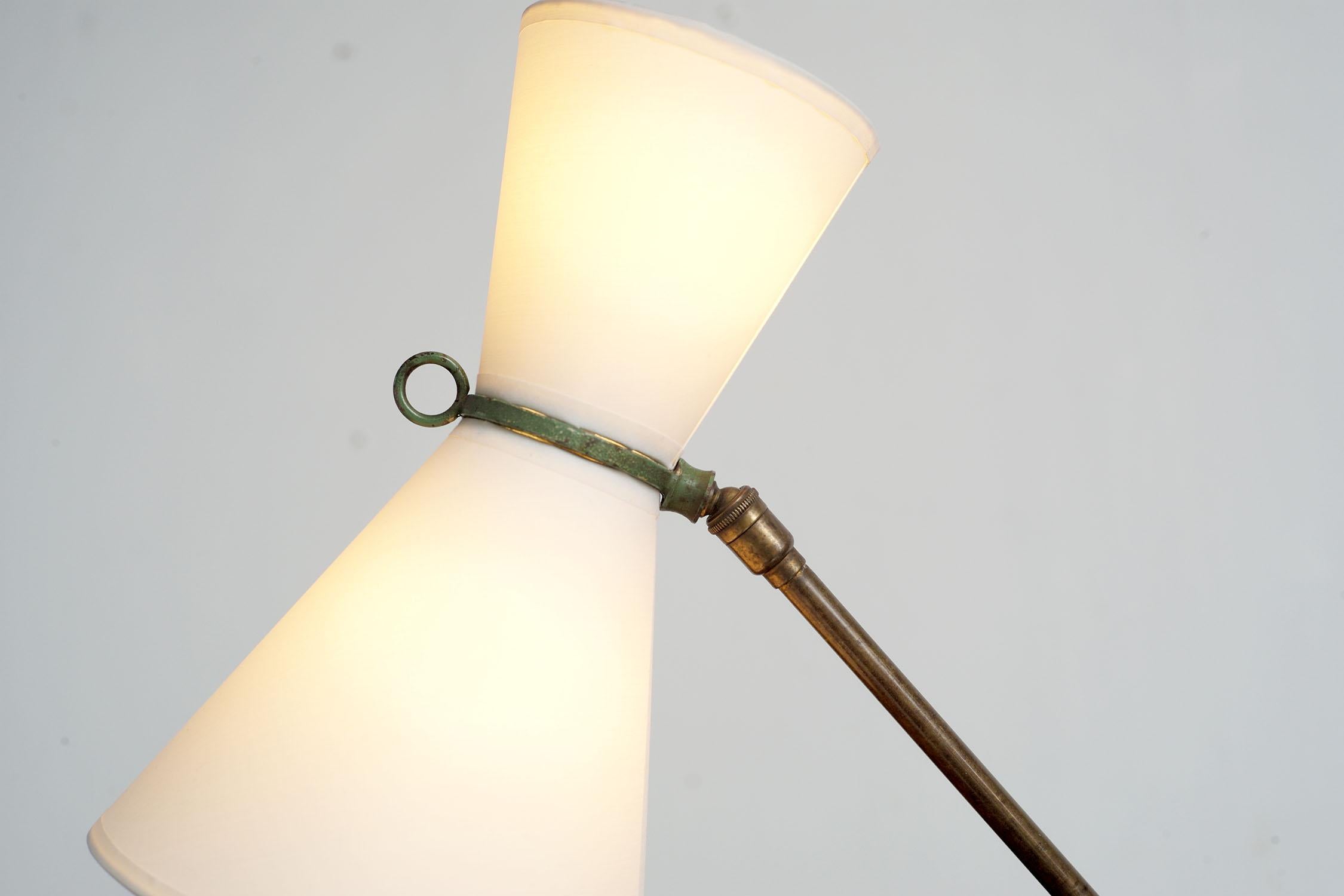 Lampe de bureau moderniste en métal laqué vert et laiton, France 1950. Le réflecteur diabolo à deux lumières est articulé par une rotule, placée sur une base métallique tubulaire. Un écrou à levier permet à l'arbre de glisser et de pivoter. Le