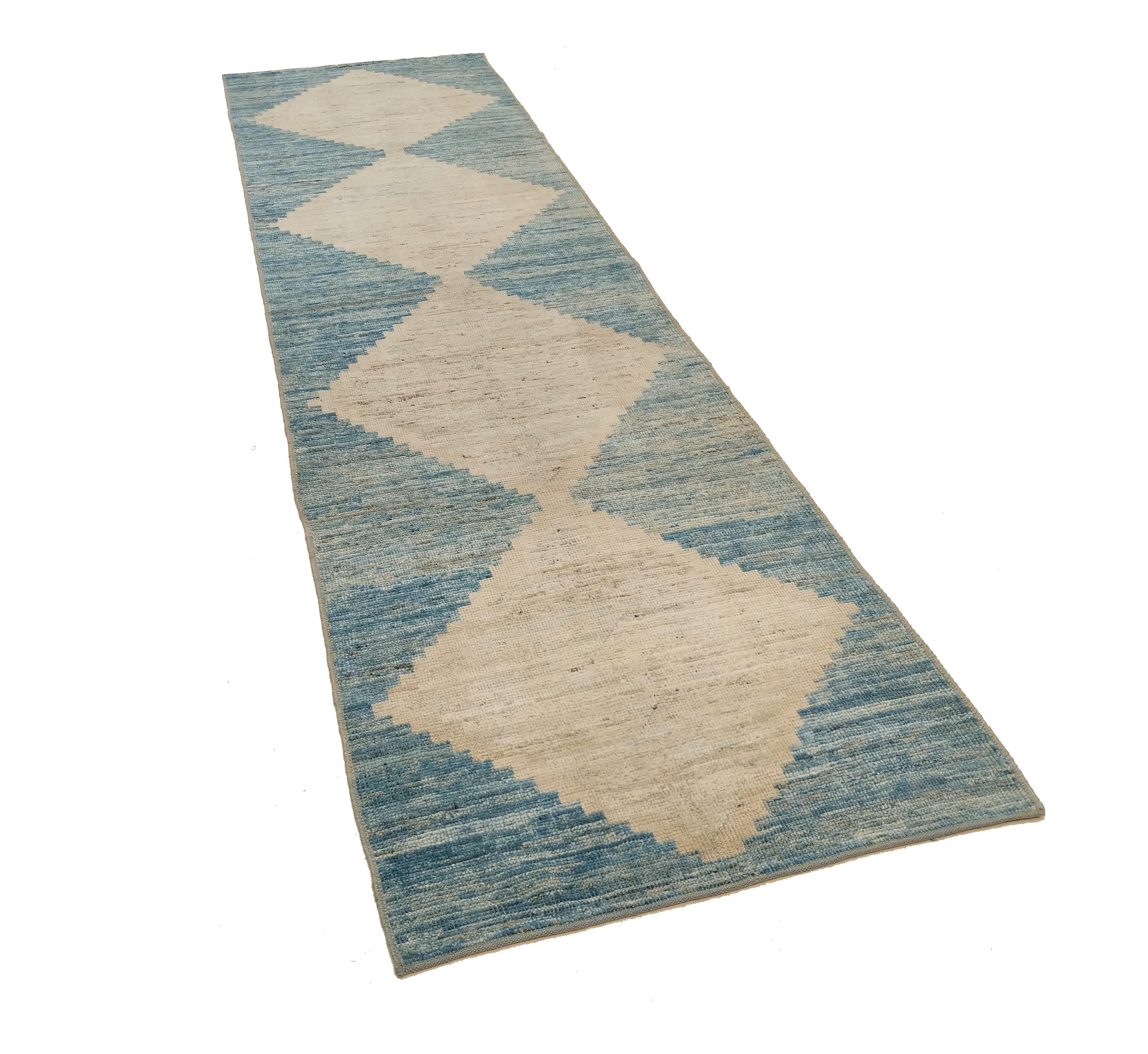 Distinguished by a finely knotted texture made precious through the use of lustrous hand-spun wool, this charming runner is decorated by four conjoined ivory diamonds with stepped outlines laid over a sky blue background. The Minimalist character of