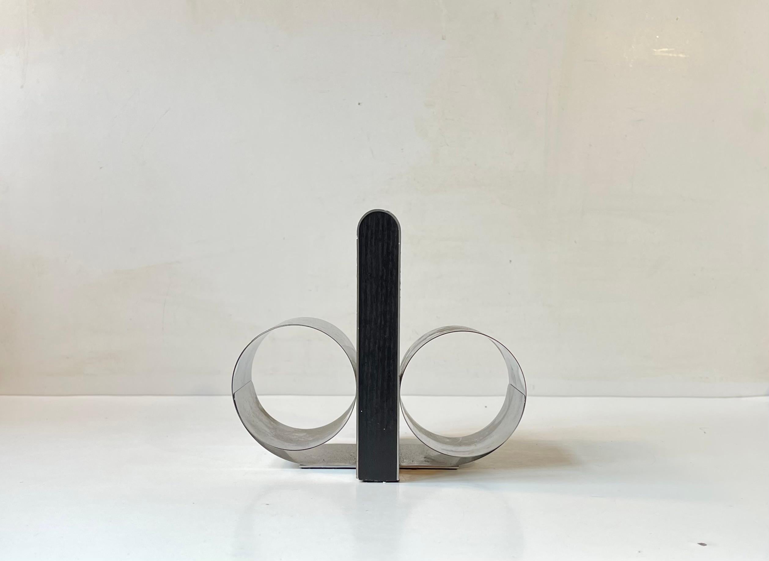 A clever design in the shape of a vinyl, CD, game(s), video or book holder with expandable rolled up sides. Its made from stainless steel and has a center in black painted wood. Designed by Andreas Mikkelsen and made by Georg Jensen in Denmark