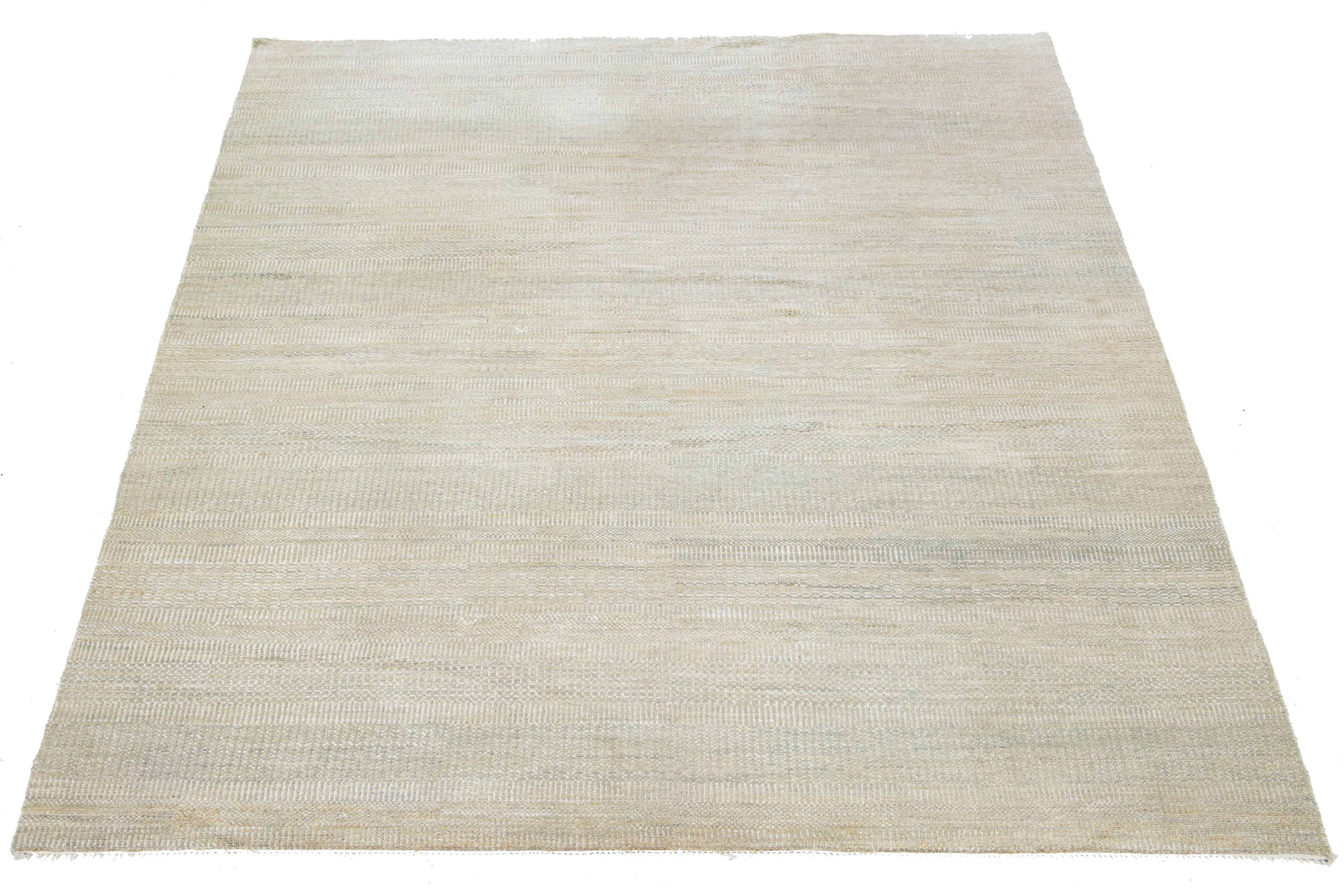 This stunning hand-knotted wool rug features a beige field and minimalist pattern with gray and golden accents, offering a transitional allure.

This rug measures 8' x 10'2