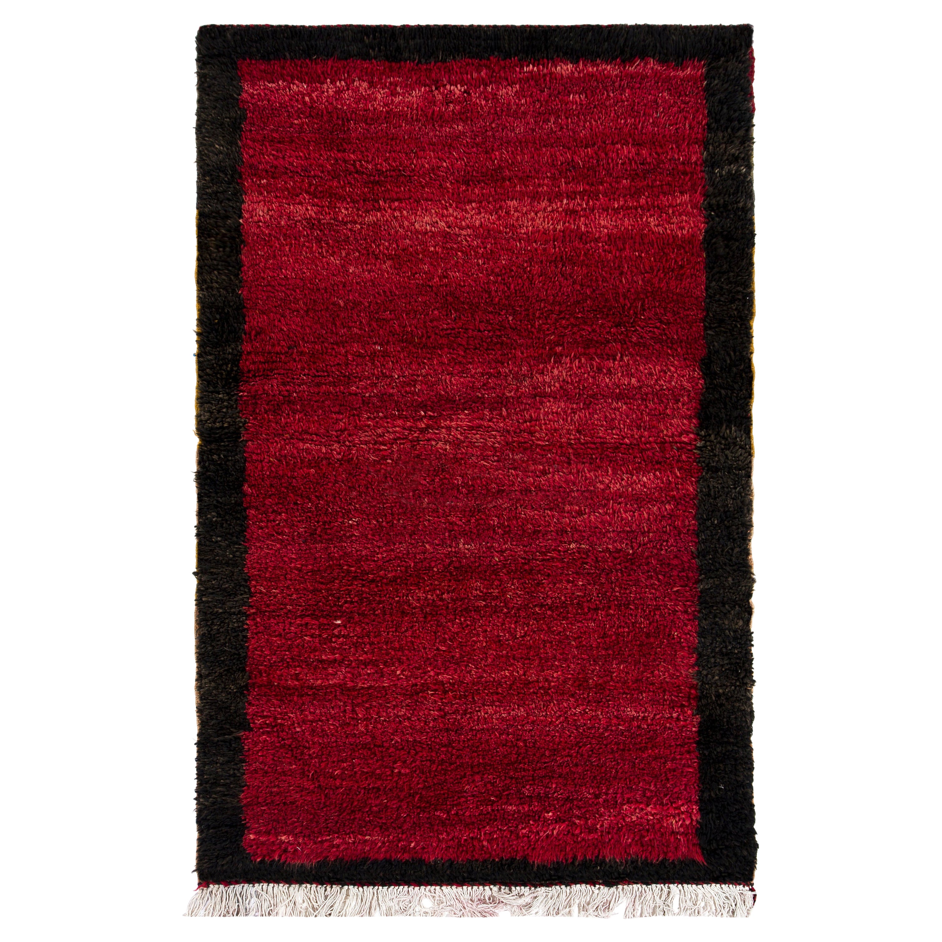 Alfombra Tulu minimalista hecha a mano con borde. Alfombra anudada a mano de color rojo. Toda la lana