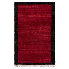 Alfombra Tulu minimalista hecha a mano con borde. Alfombra anudada a mano de color rojo. Toda la lana