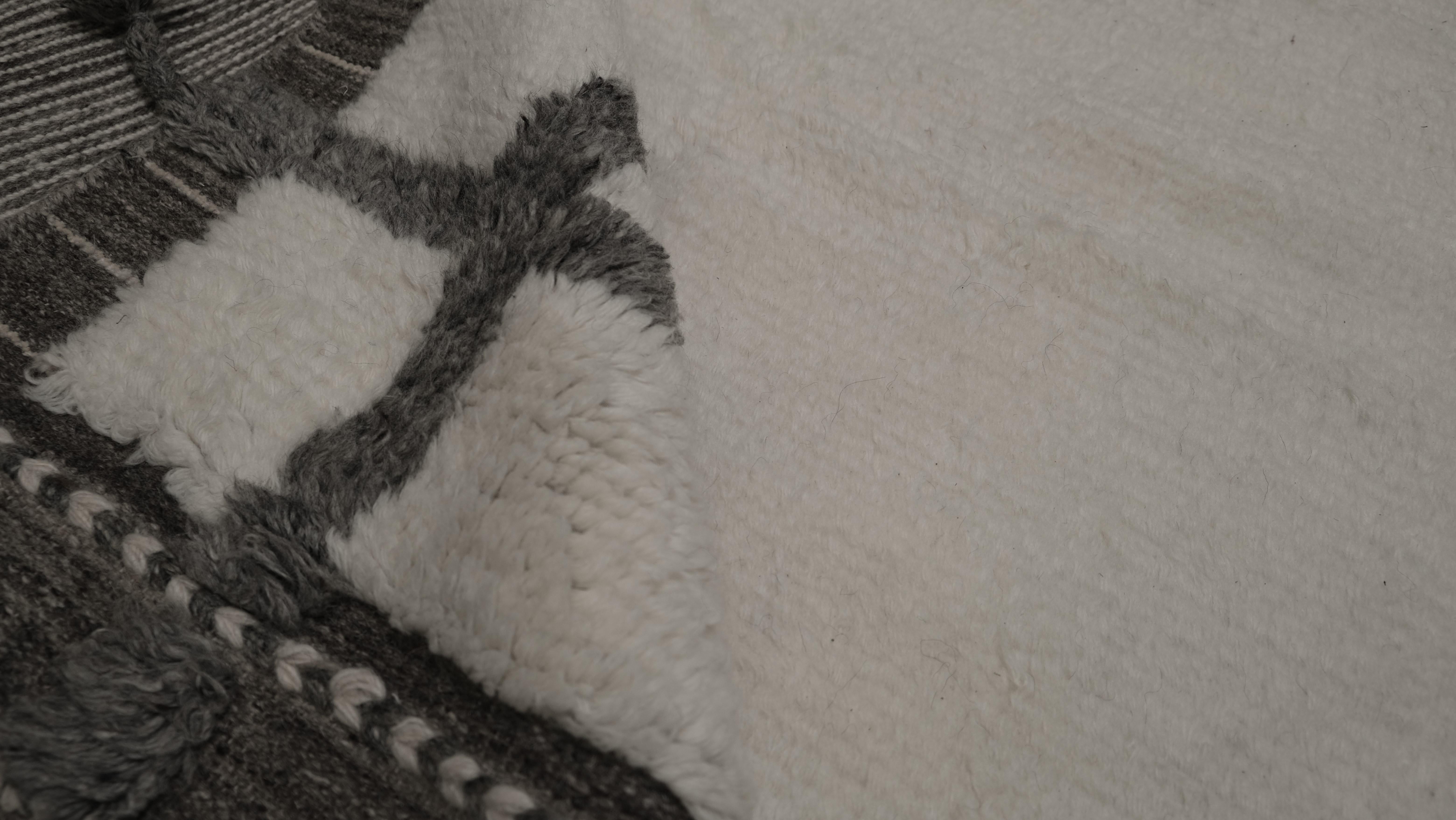 Ajoutez une élégance intemporelle à votre espace avec ce tapis en laine noué à la main, doté d'un design minimaliste encadré de gris et d'ivoire. Le champ ivoire épuré du tapis est accentué par une bordure audacieuse à double ligne, créant un