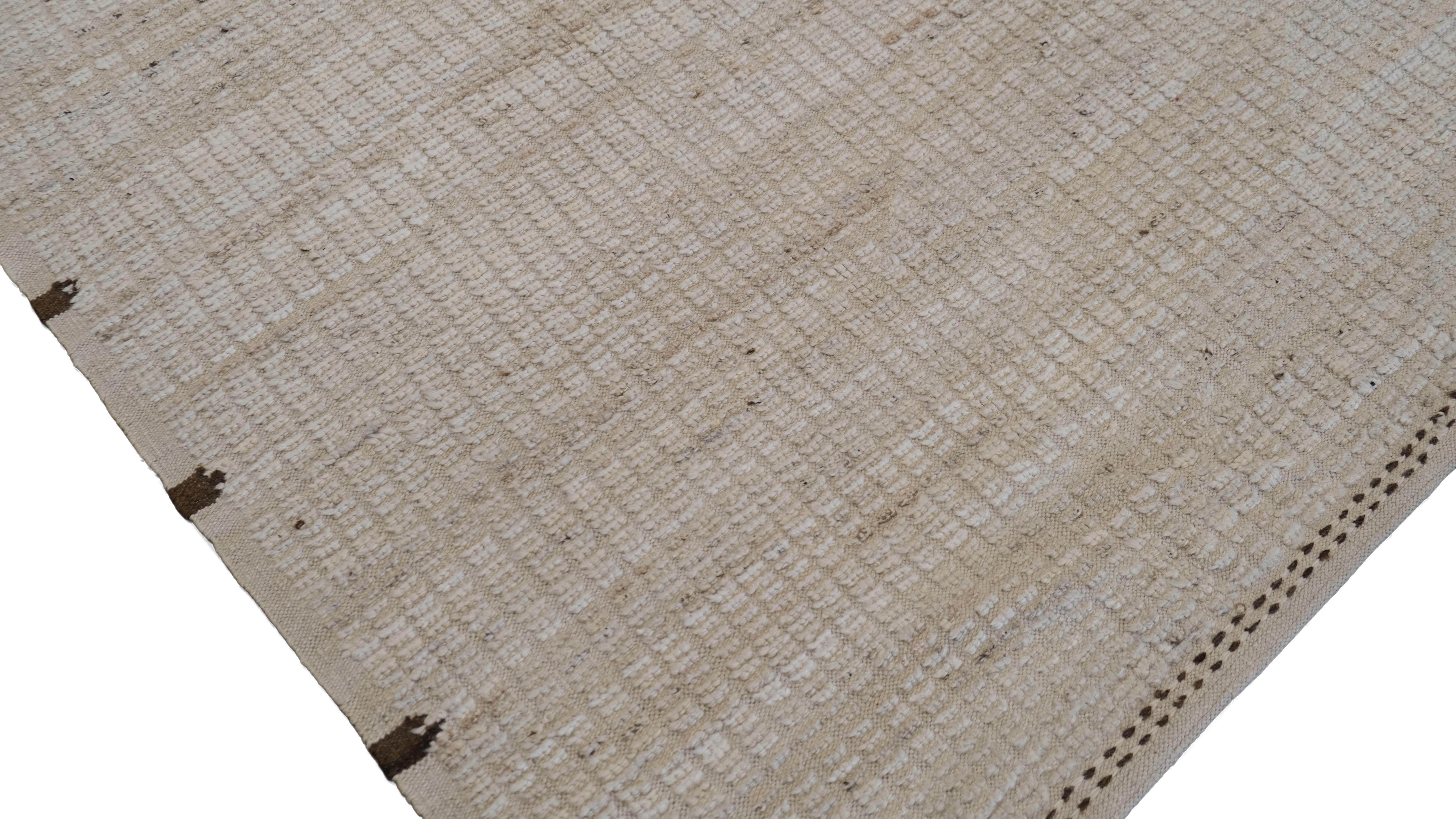 Dieser handgeknüpfte Wollteppich ist ein Beweis für die Schönheit der Schlichtheit und der traditionellen Handwerkskunst. Das minimalistische Design des Teppichs zeichnet sich durch eine subtile lineare Struktur aus, die einen unaufdringlichen und