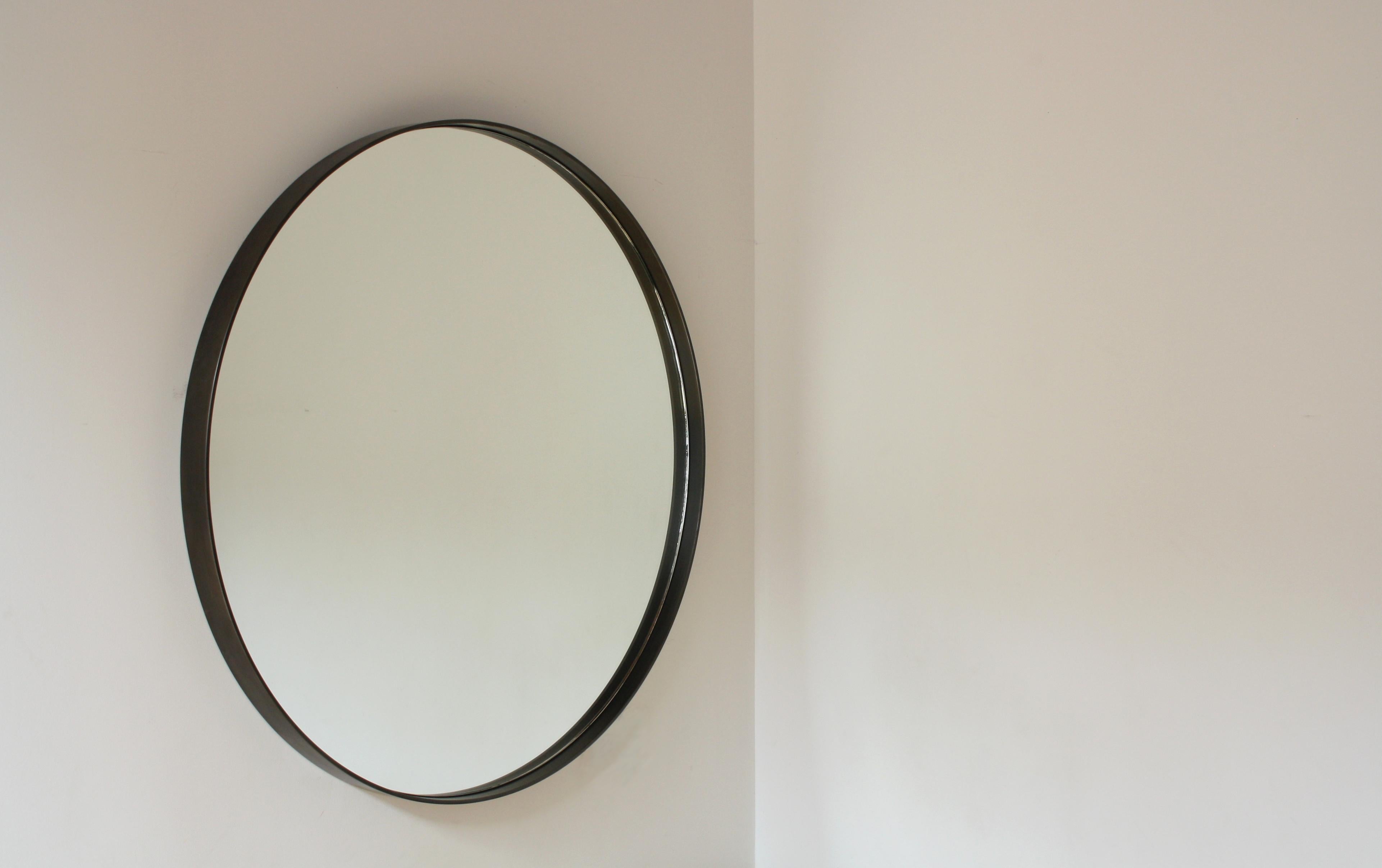Handmade in Chicago by Laylo Studio, this customizable mirror features a clear, round mirror with polished edges centred inside a blackened steel frame. The circular metal frame is polished, gently brushed and darkened using a gun-blue patina that