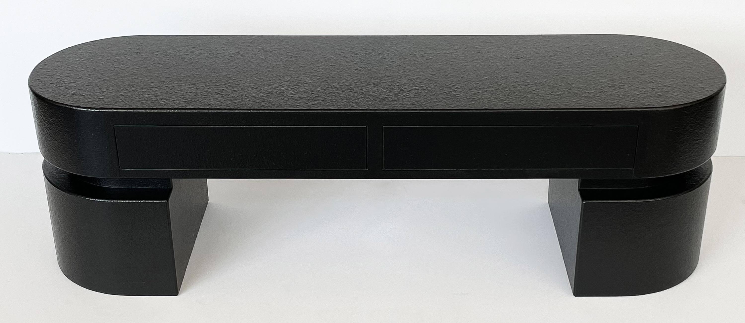 Minimalist modern black narrow coffee table / bench, circa early 1980s. A long narrow pill shaped top with curved pedestal legs at each end. The legs have a 2