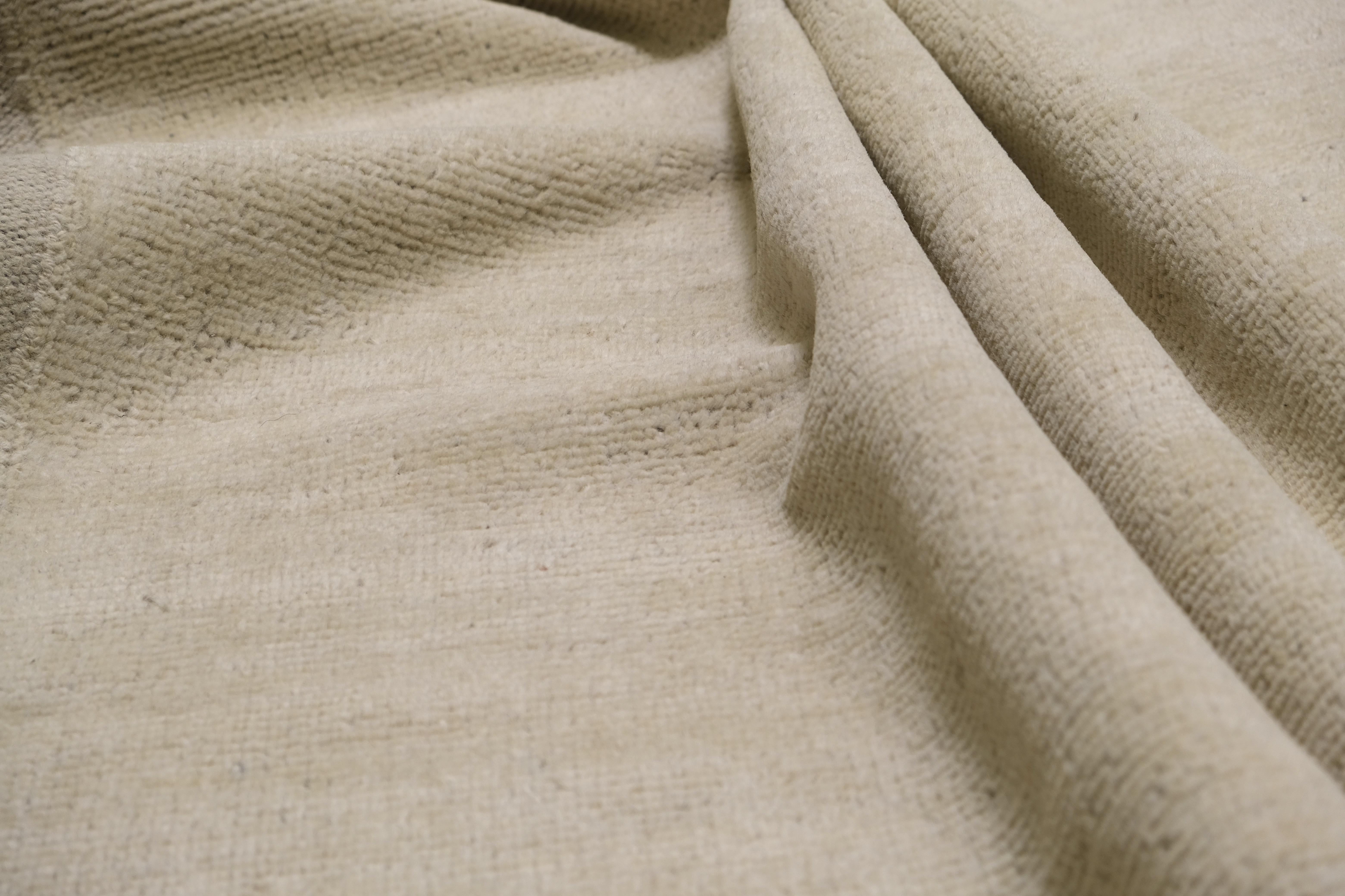 Dieser handgeknüpfte Wollteppich ist ein raffiniertes Beispiel für modernes, minimalistisches Design, das durch seine subtile Textur und seine gleichmäßige Farbgebung unaufdringliche Eleganz ausstrahlt. Der von erfahrenen Handwerkern mit