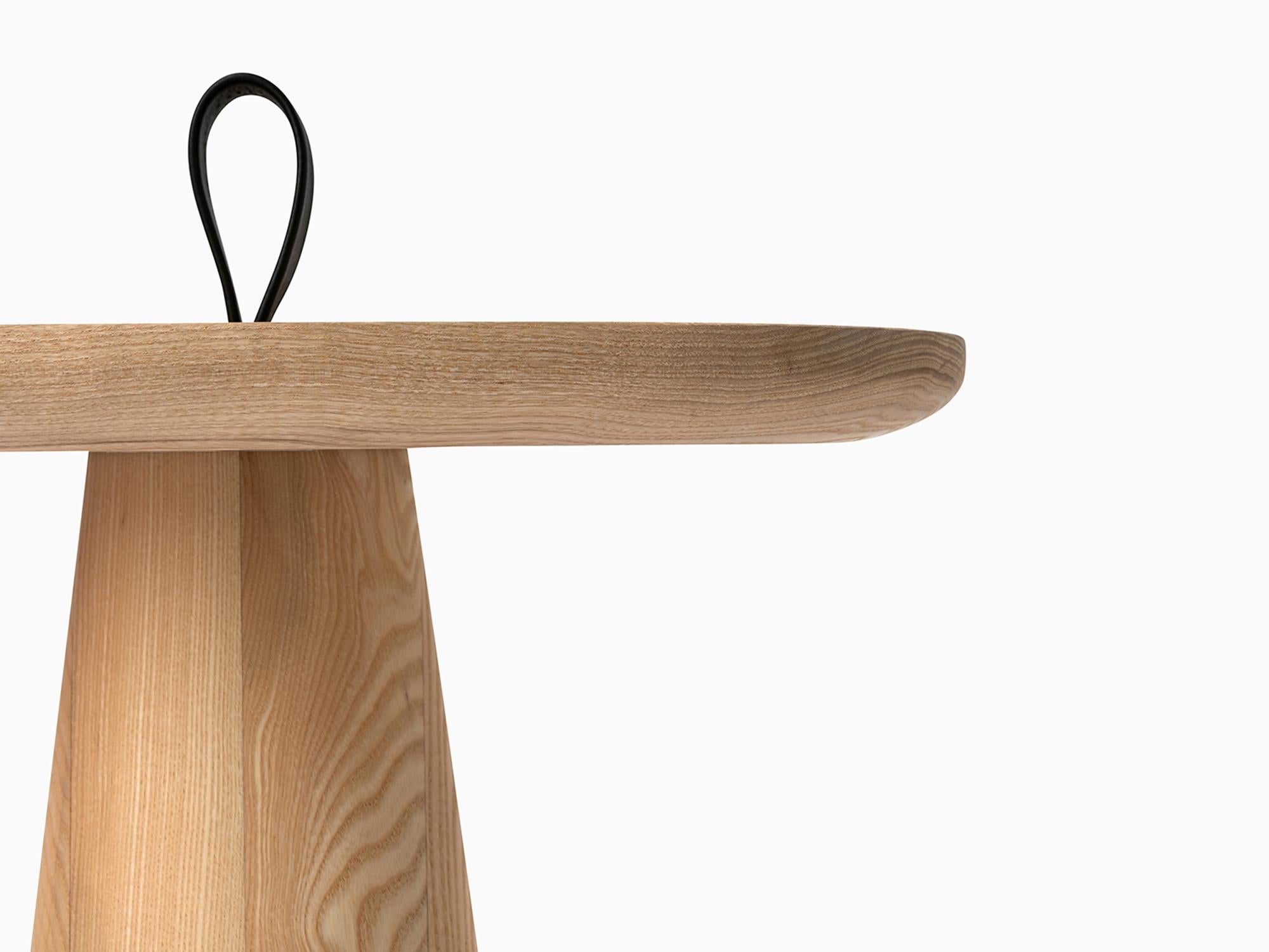 Der minimalistische Migo-Tisch besteht aus zwei Teilen: einer Tischplatte und einem konisch geformten Sockel, dessen Oberseite mit einem Riemen zum Anheben endet.

Die weiche und freundliche Form der Platte macht den Tisch für verschiedene