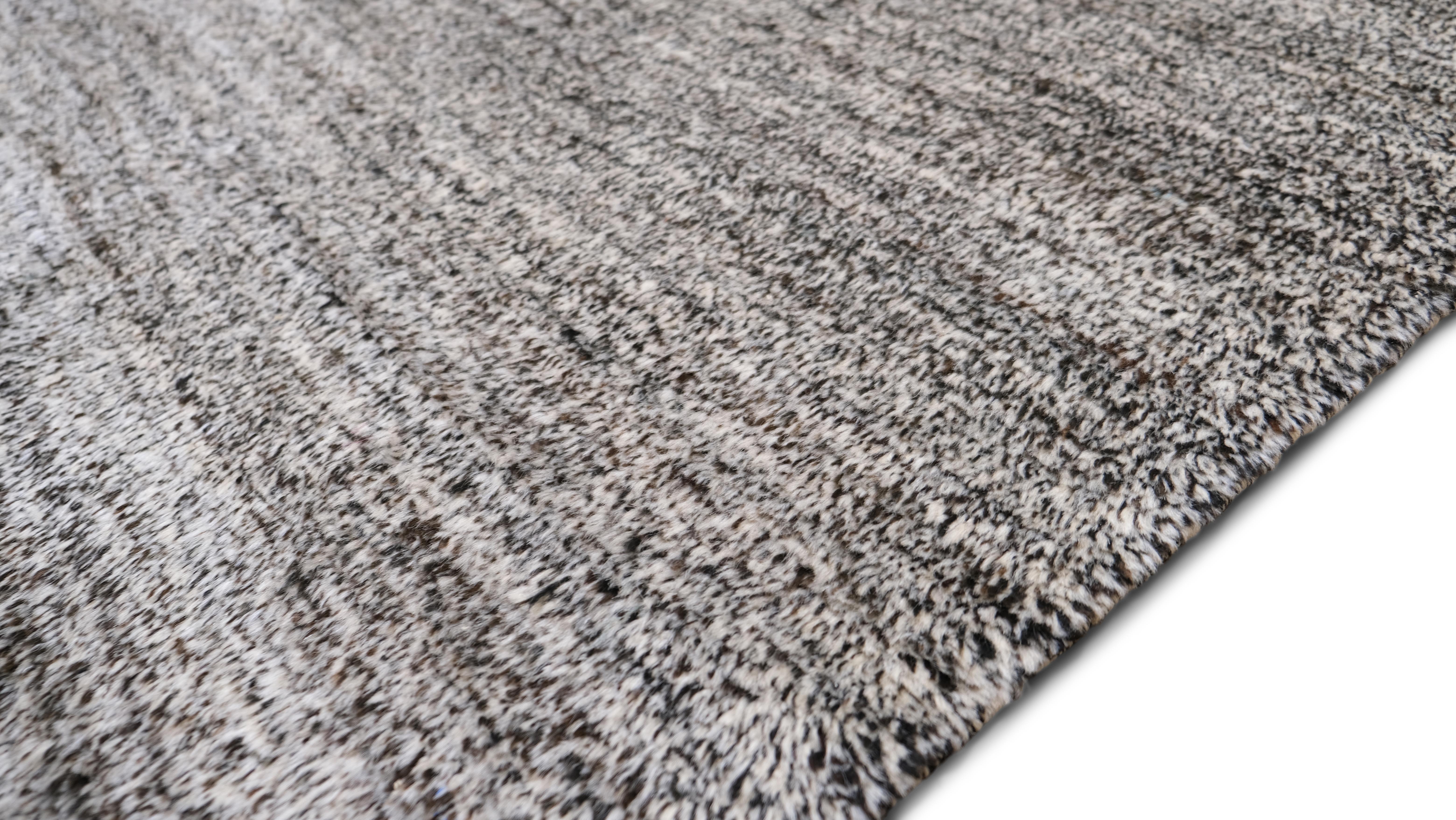 This hand-knotted wool rug embodies understated luxury with its minimalist aesthetic and rich texture. Woven from natural wool, it features a subtle blend of neutral tones, creating a versatile and timeless piece that enhances modern, Scandinavian,