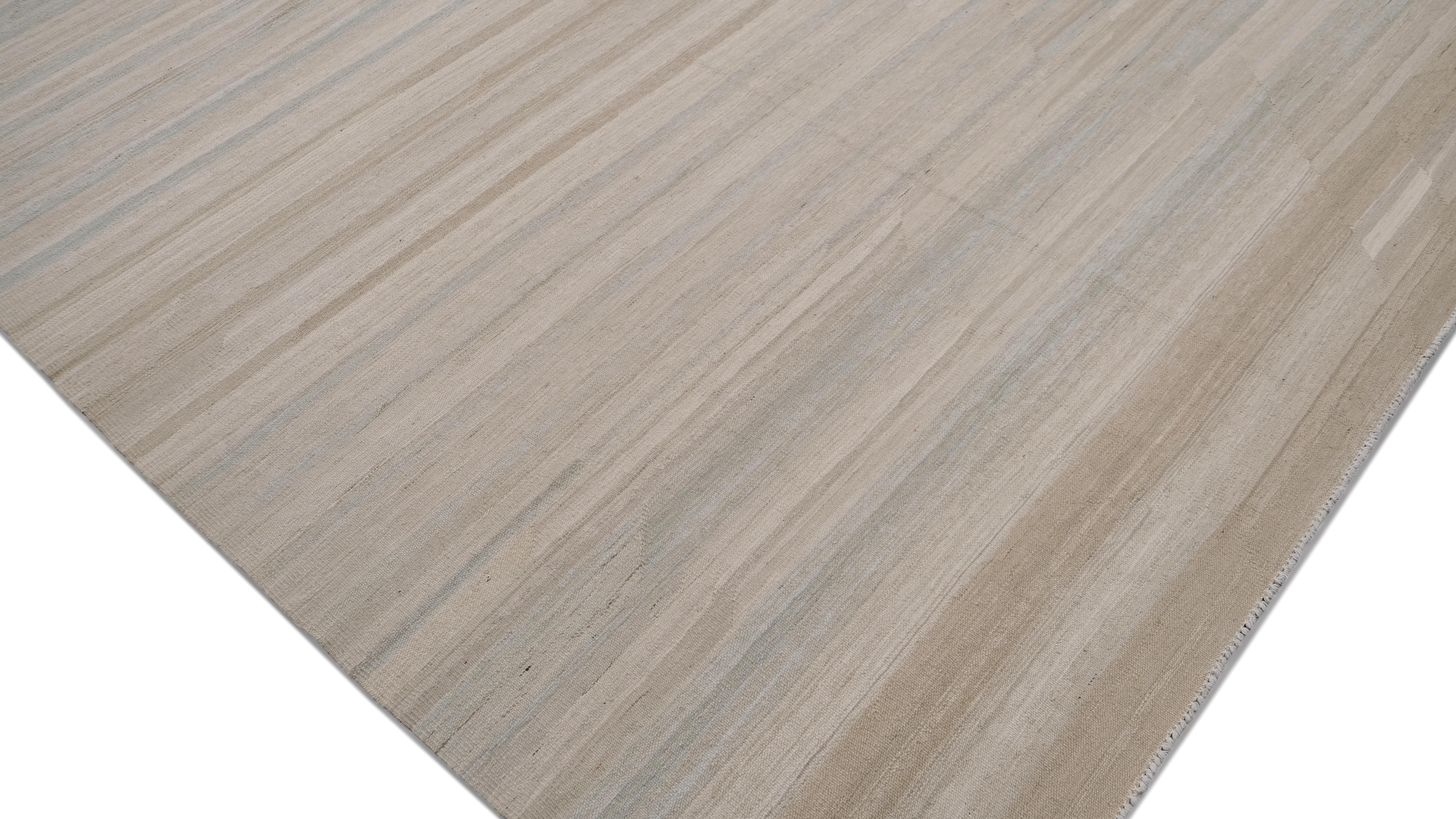 This handwoven wool rug embodies the essence of minimalist elegance with its subtle, organic striped pattern in soft, earthy hues. Featuring a blend of beige, ivory, taupe, and light blue, this rug exudes a natural, understated sophistication,