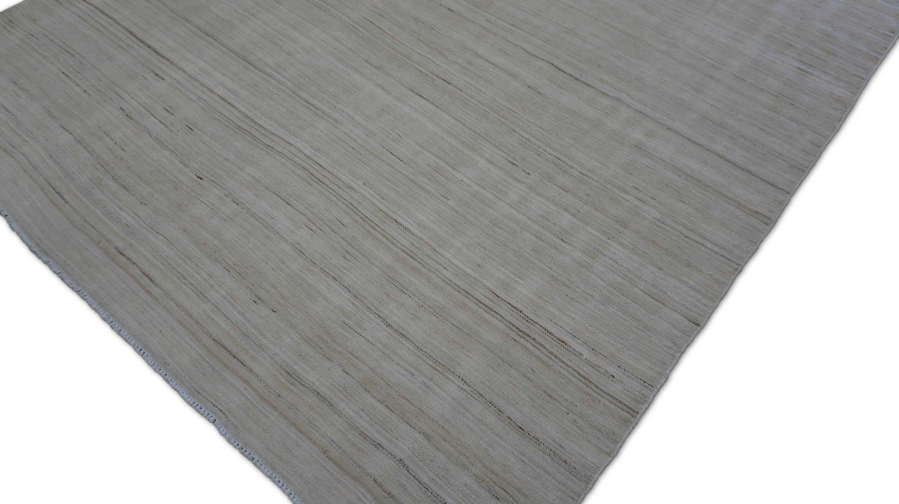 Este  La alfombra plana de lana es una refinada expresión de diseño minimalista. Tejida con precisión con lana hilada a mano, presenta una paleta suave y neutra con delicadas estrías horizontales irregulares en tonos neutros. Estas discretas