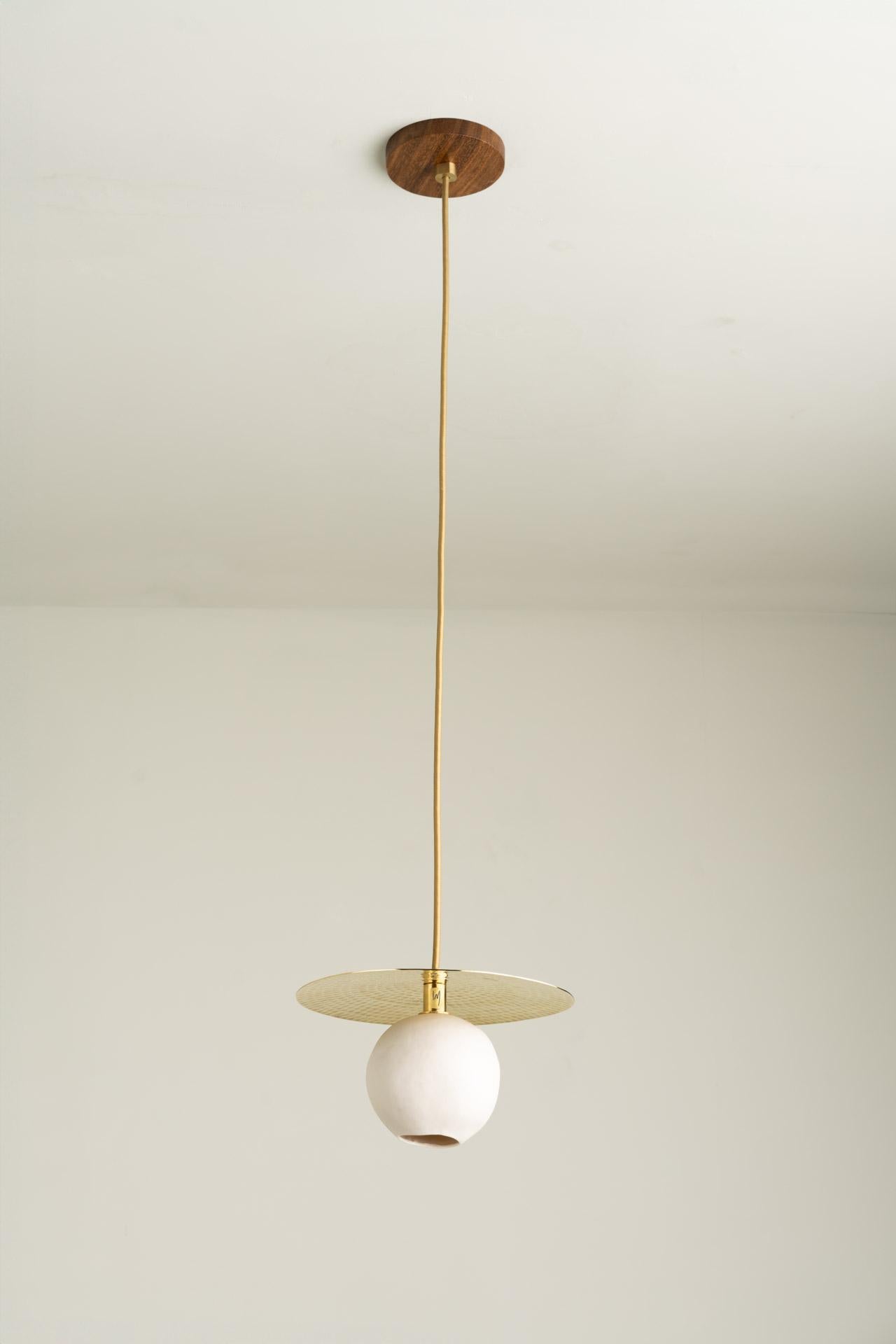 COMETA pendant light was designed for the Atomic collection by Mexican artist Isabel Moncada.

The hand-hammered brass disc is the artisanal work that stars in this minimalist piece. In addition to giving character to the design, it has the function