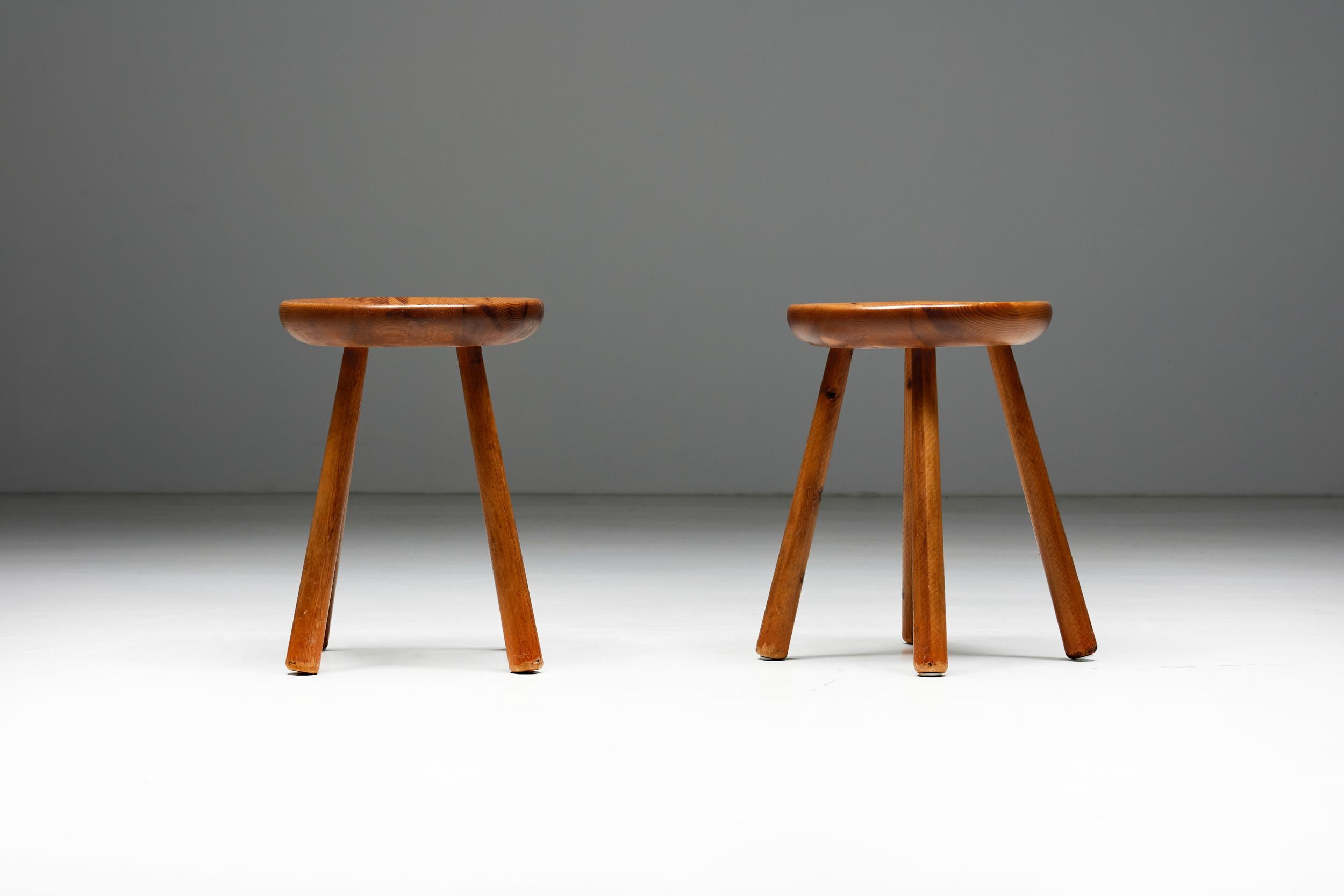 French minimalist pine stools, a timeless embodiment of mid-century elegance. Crafted circa 1950, these stools boast a distinctive design featuring four sleek legs and a subtly concave round seat, reminiscent of the iconic work of Charlotte