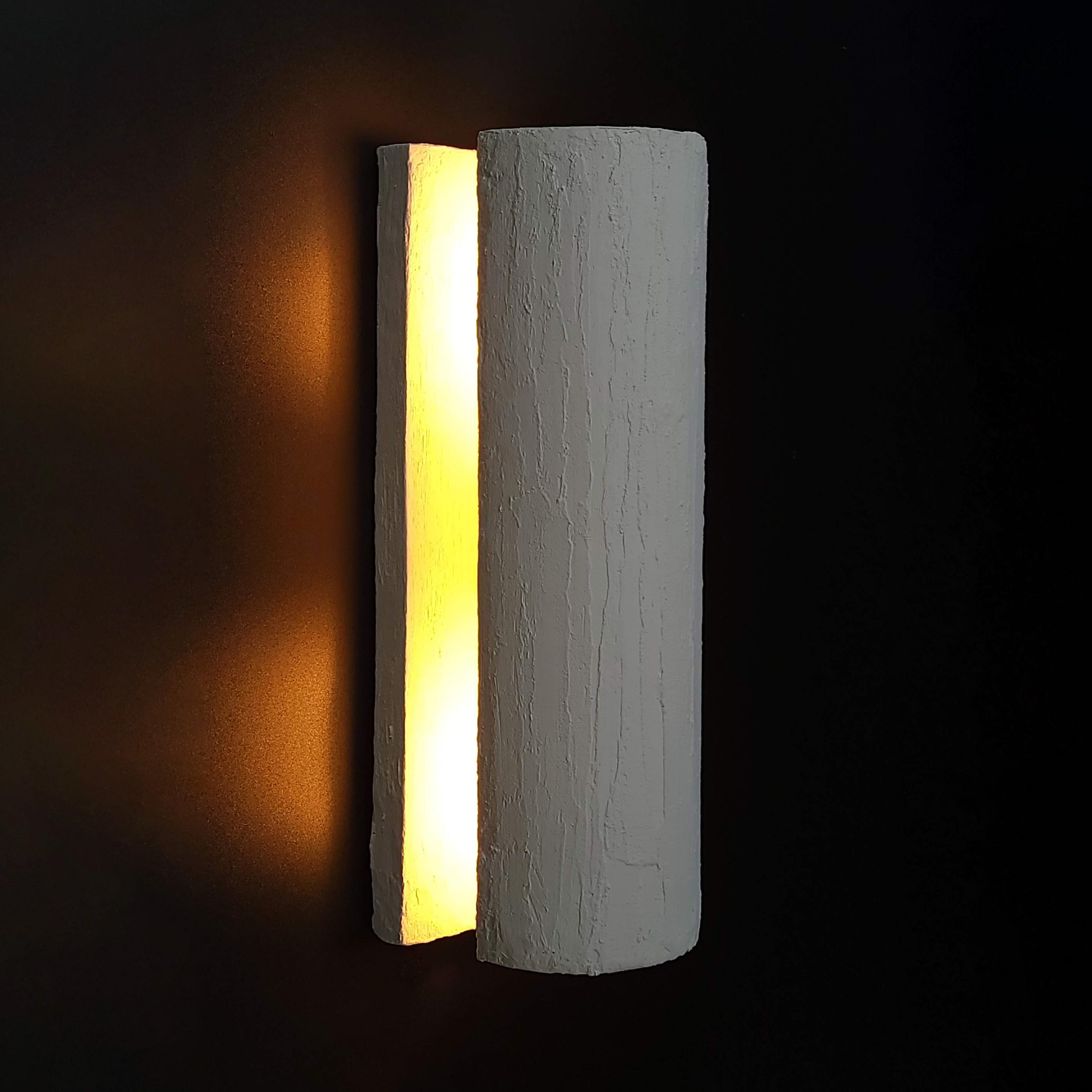 Introducing our Minimalist Plaster Cylinder Wall Sconce, designed to infuse your space with serene lighting and a touch of modern simplicity. This fixture's cylindrical form is a nod to minimalist aesthetics, focusing on the pure interplay of light