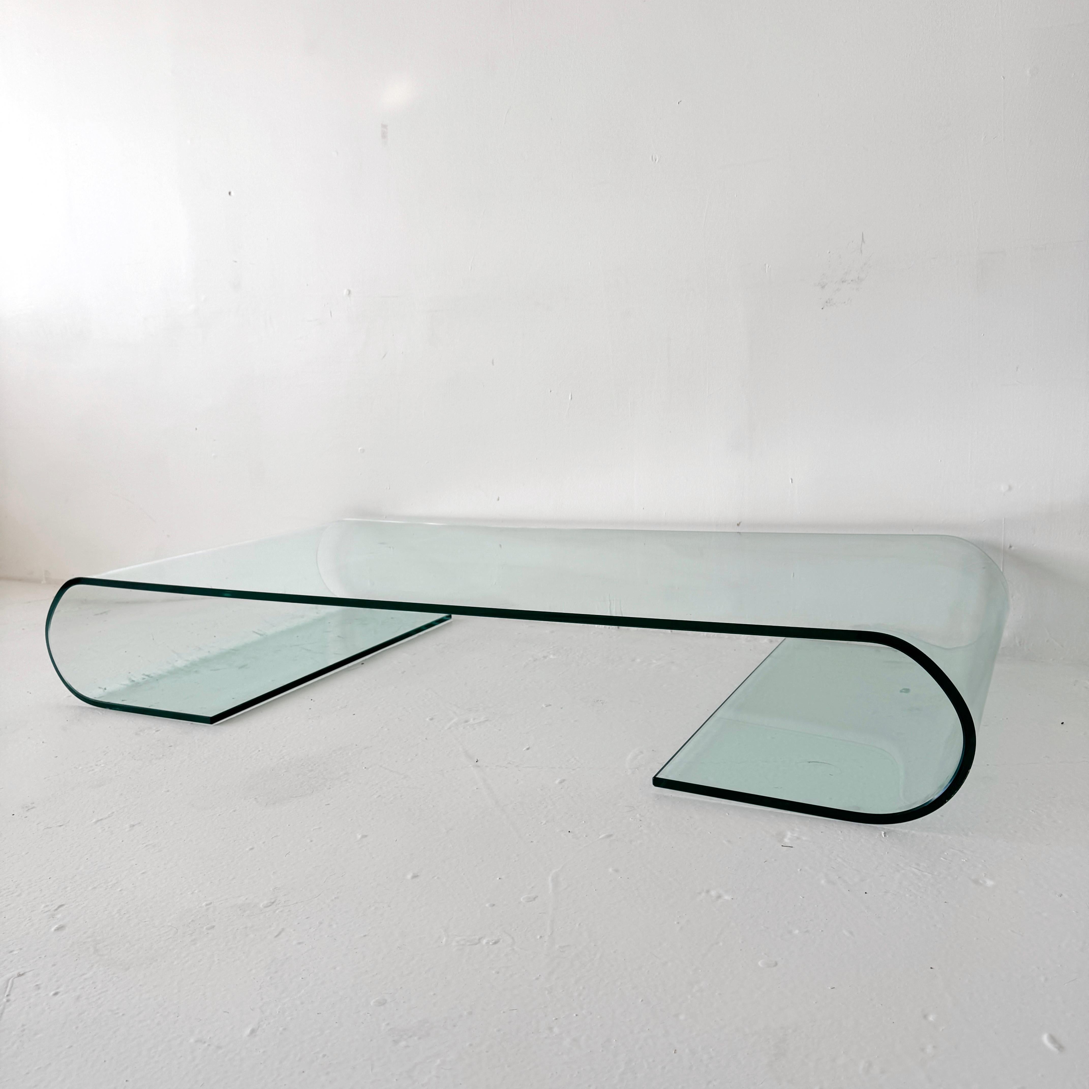 Escultural mesa de centro postmoderna con forma de voluta, de grueso cristal templado. Diseño minimalista con proporciones perfectas: la única hoja de cristal doblada se enrolla en suaves bordes curvados, creando a la vez estabilidad y ligereza