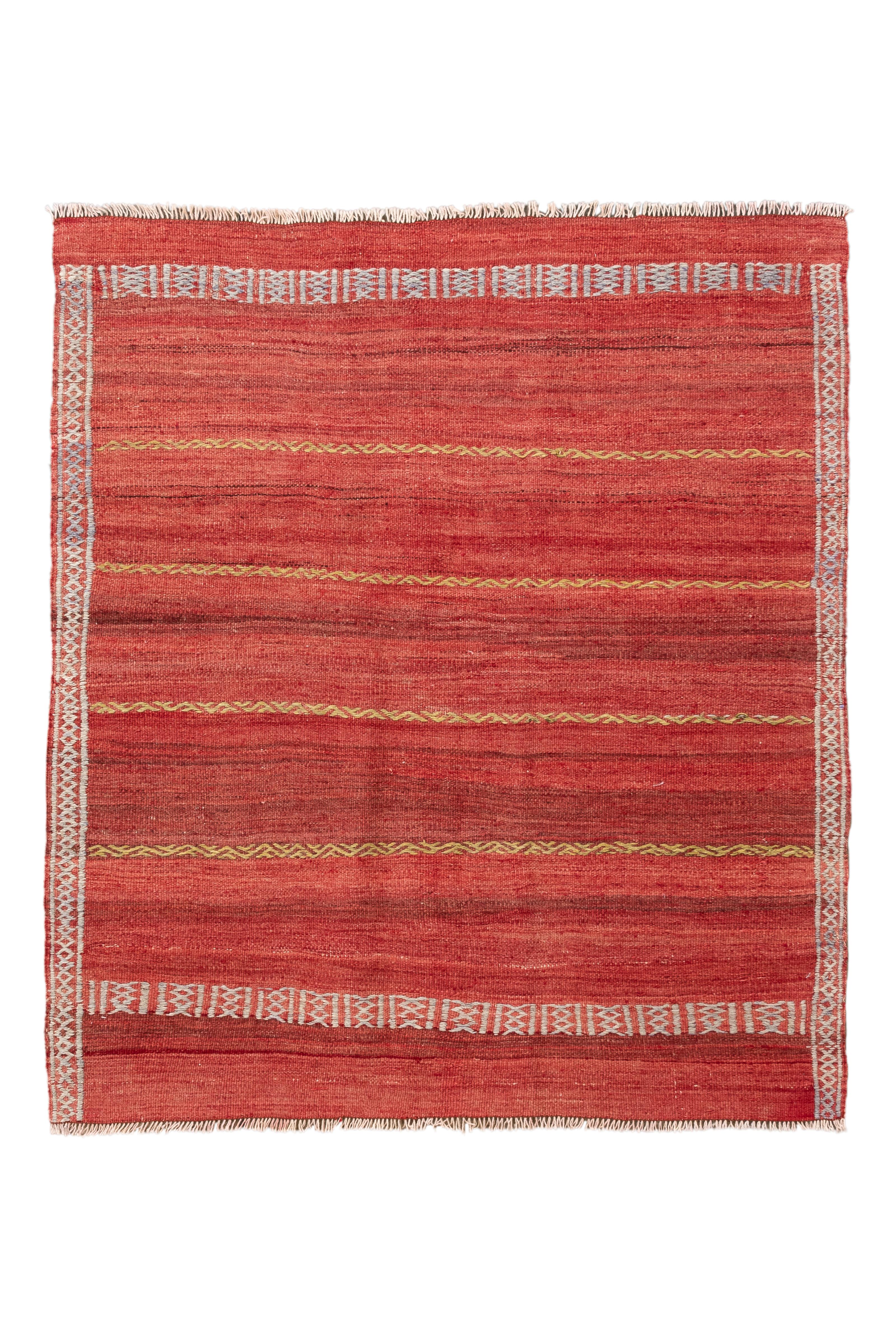 Questo Kilim turco vintage, raffinato e minimalista, è tessuto a mano e presenta un campo rosso splendidamente abraso con una disposizione ritmica di strisce orizzontali e morbidi motivi tribali. Sottili accenti gialli a zig zag spezzano il campo in