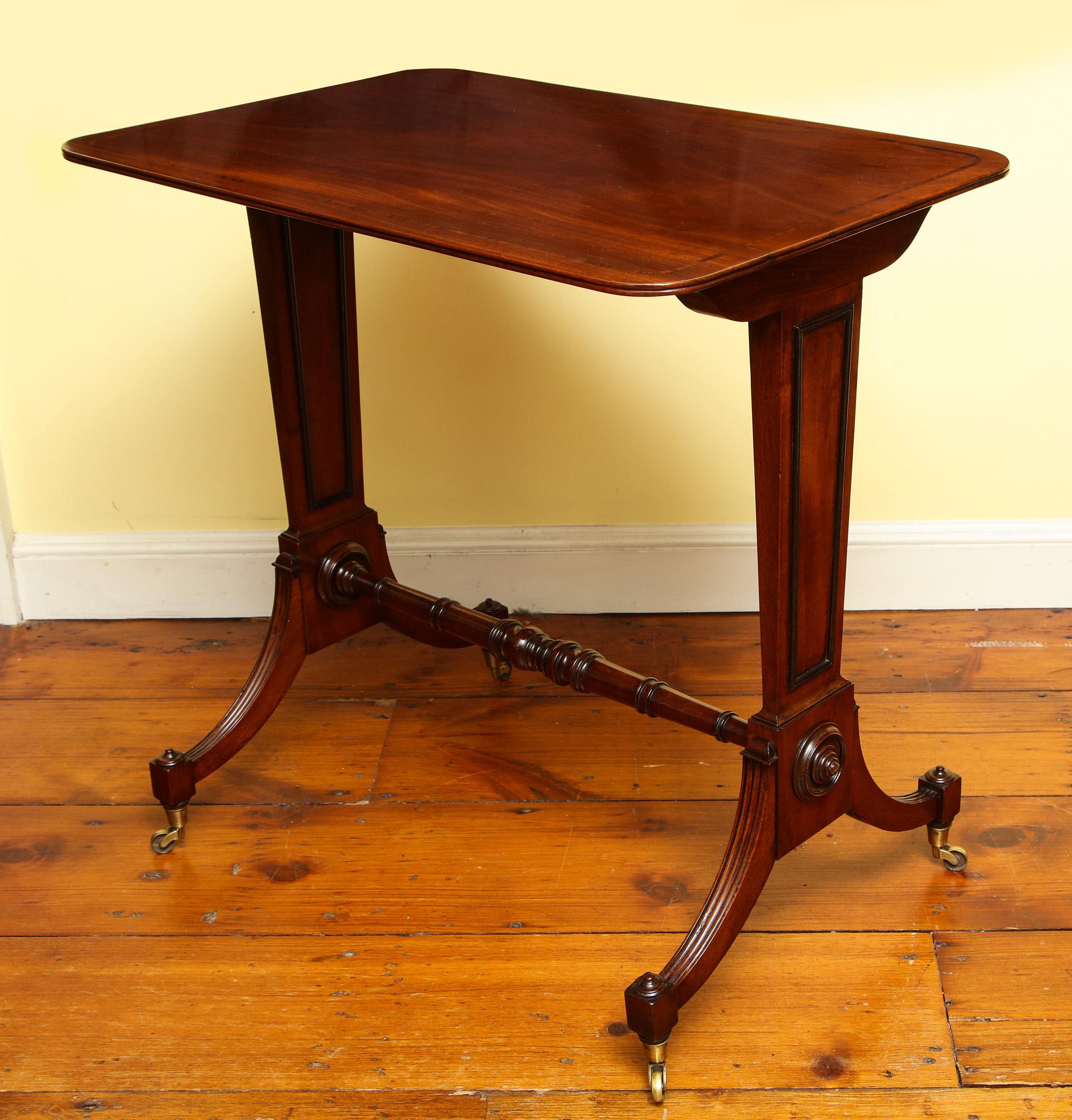 Fine Minimalist Regency mahogany and ebonized writing table, the double reeded rectangular top with rounded corners and inlaid with rosewood crossbanding, on twin tapering trestle supports with applied ebonized moulding, a finely turned stretcher
