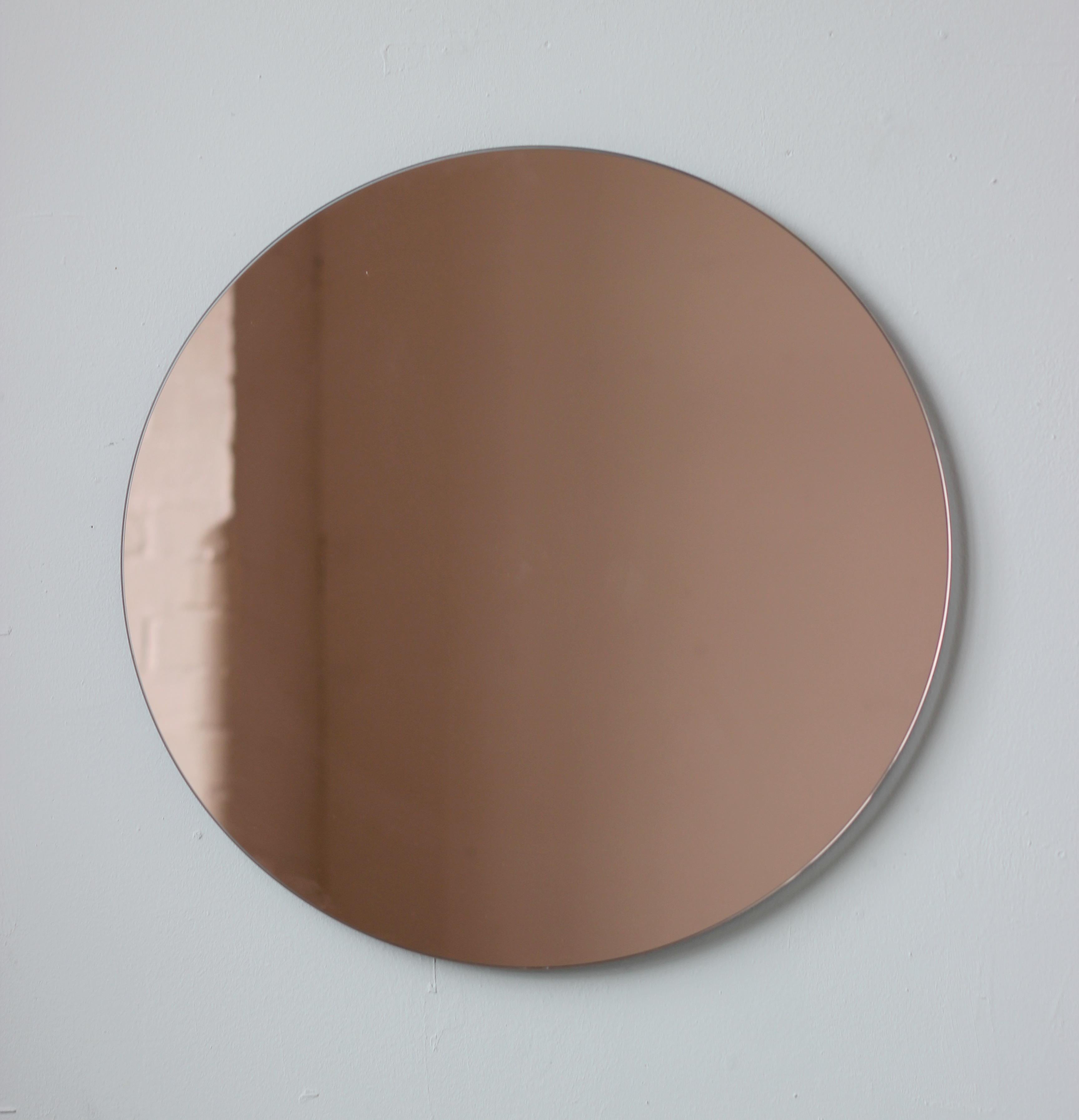 Charming and minimalist rose gold / peach tinted round frameless mirror with a floating effect. Quality design that ensures the mirror sits perfectly parallel to the wall. Designed and made in London, UK.

Fitted with professional plates not visible