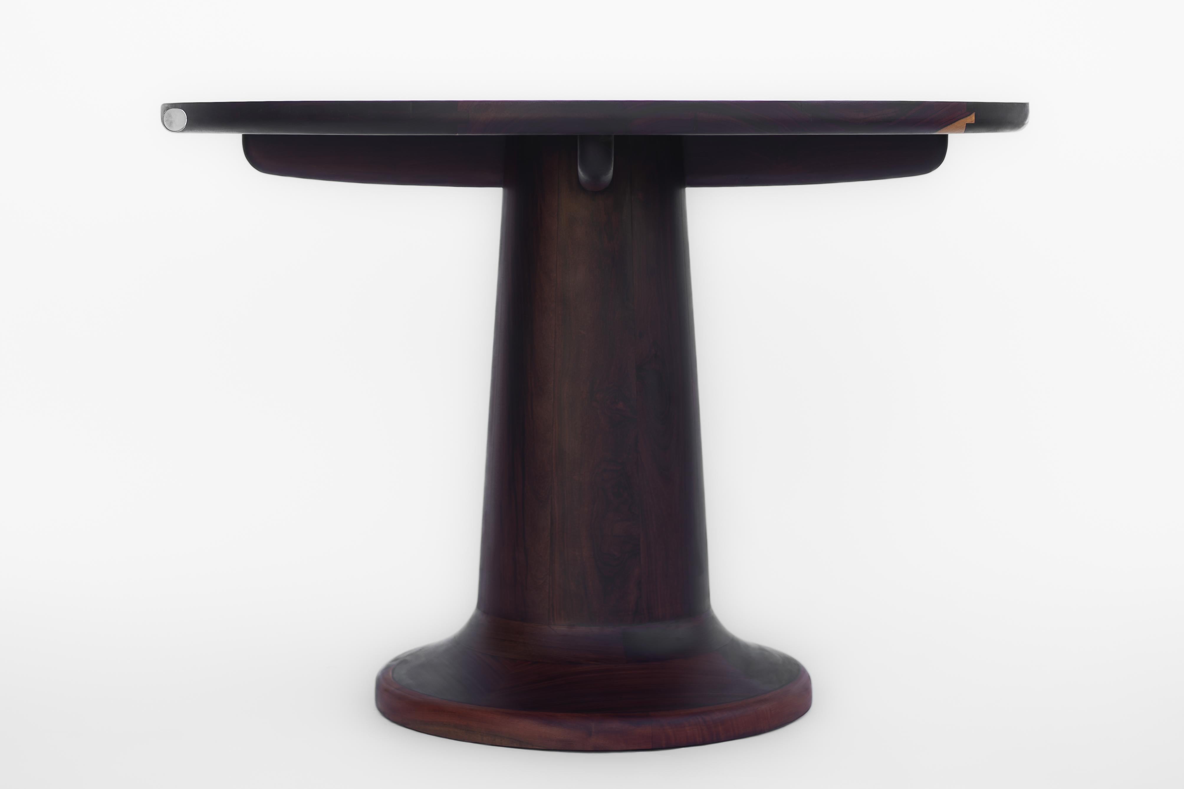 Une pièce simple mais classique, fabriquée en bois Katalox - Mexican Ebony. Le ton naturel violet foncé du bois donne beaucoup de caractère à la table, tandis que ses formes incurvées lui confèrent du raffinement. Pour sa construction, nous