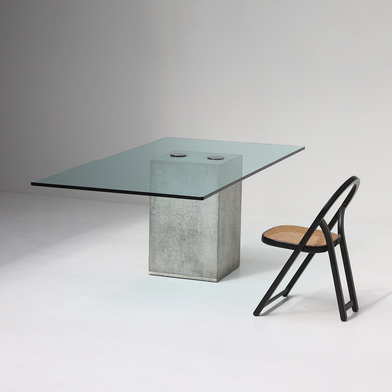 This minimalist dining table was designed and produced by Saporiti in 1972. This Sapo model comes in a coffee- and dining table and has a timeless yet inventive design. The base is made of concrete, holding a glass table top which is attached with