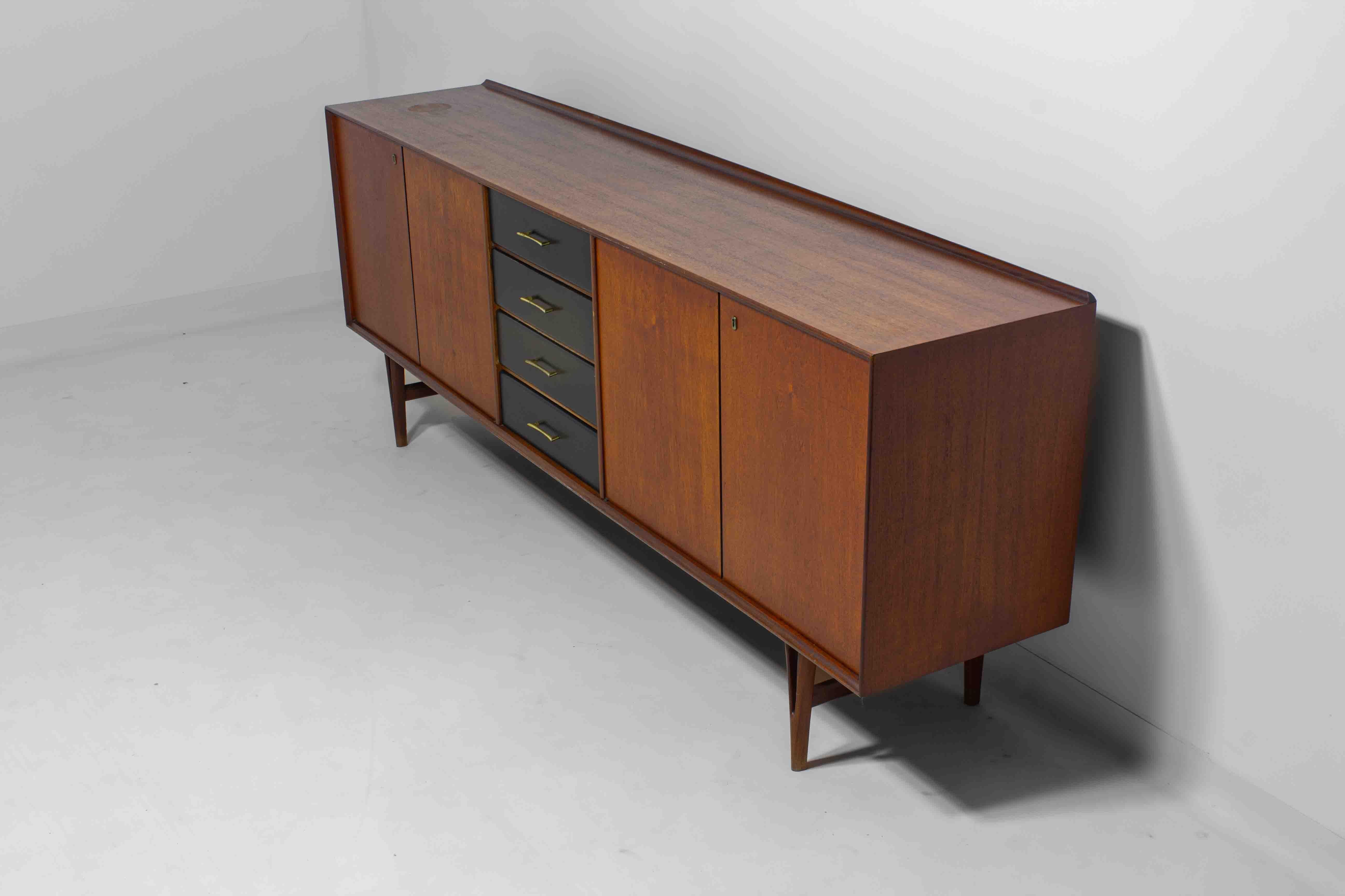 Ce buffet belge de Van Pelt, datant des années 1960, a un corps en teck avec des tiroirs noirs et des poignées en laiton. Il offre un mélange d'armoires et de tiroirs pour un grand nombre de rangements. Les pieds en forme de V lui confèrent une